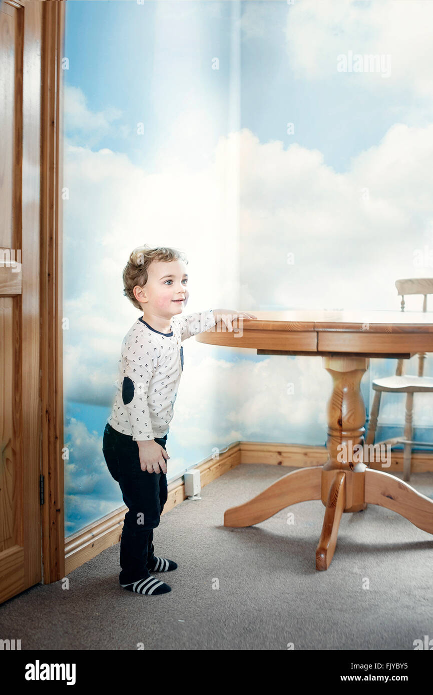 kleiner Junge spielt den Holztisch in der Küche Stockfoto