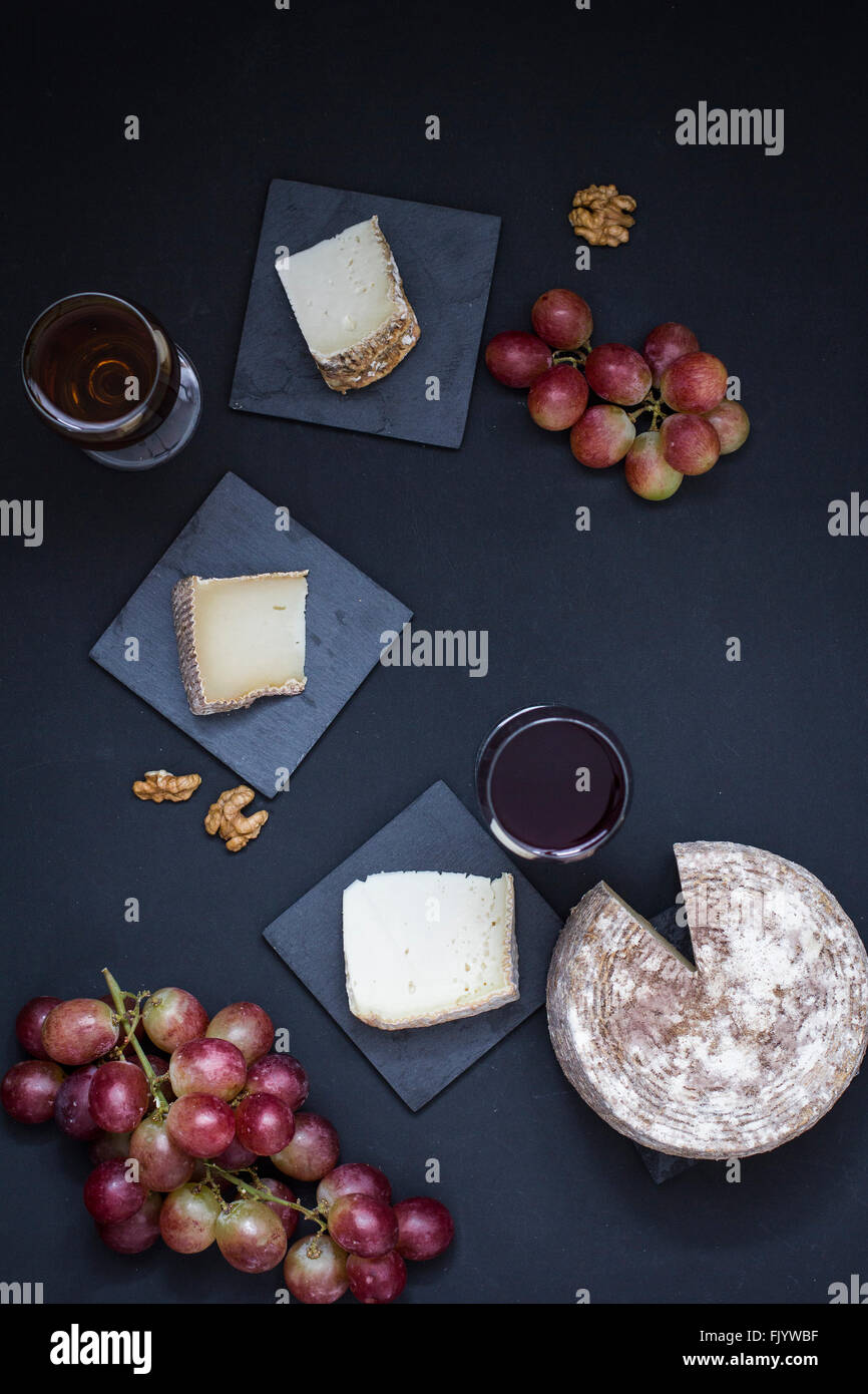Käse, Wein und Trauben auf schwarzem Hintergrund Stockfoto