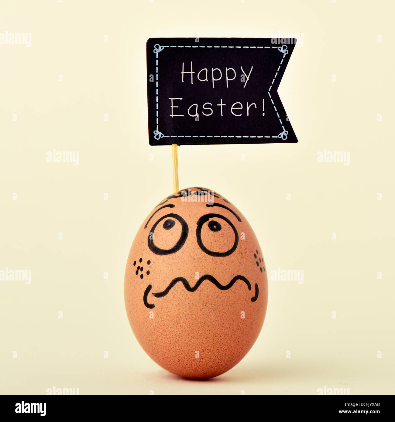 eine braune Ei verziert mit lustigem Gesicht mit einem Black Flag-förmigen Schild mit dem Text Frohe Ostern auf eine wollweiße staatlich Stockfoto