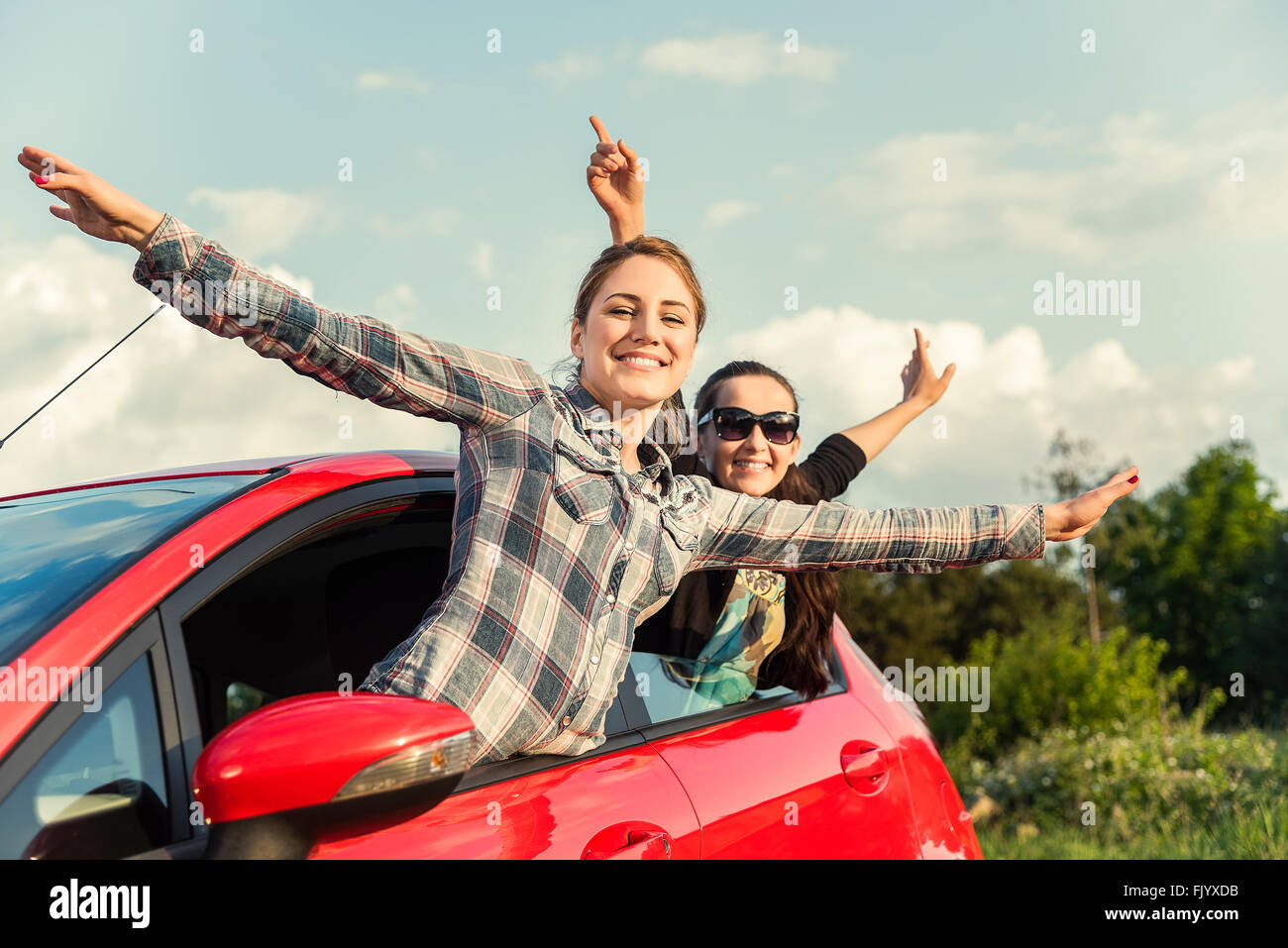 Mädchen in einem roten Auto bei Sonnenuntergang. Reisekonzept. Stockfoto