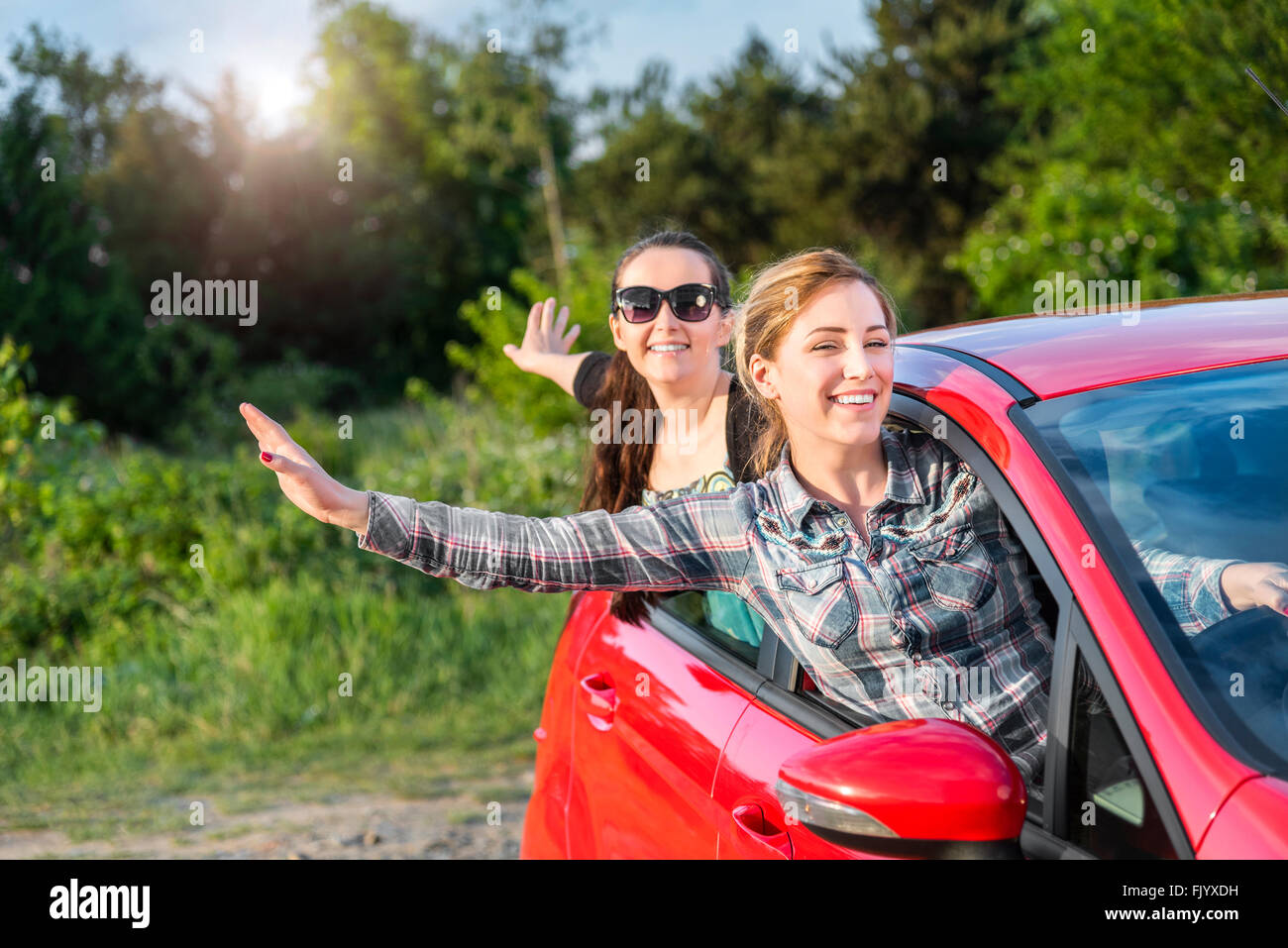 Mädchen in einem roten Auto bei Sonnenuntergang. Reisekonzept. Stockfoto