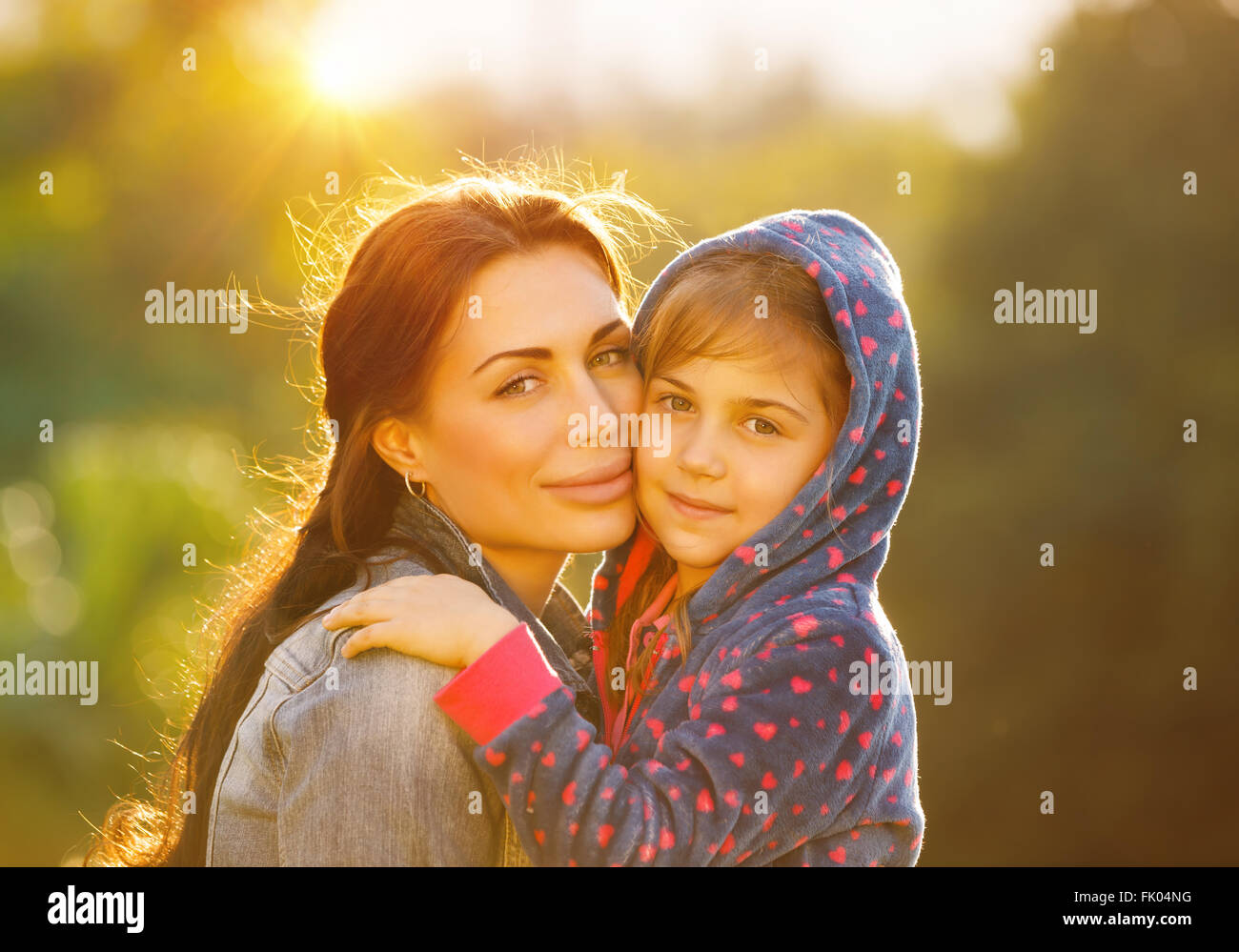 Porträt von schöne junge Mutter mit ihrer süßen kleinen Tochter im Freien bei hellem Sonnenlicht, Zeit miteinander zu verbringen Stockfoto