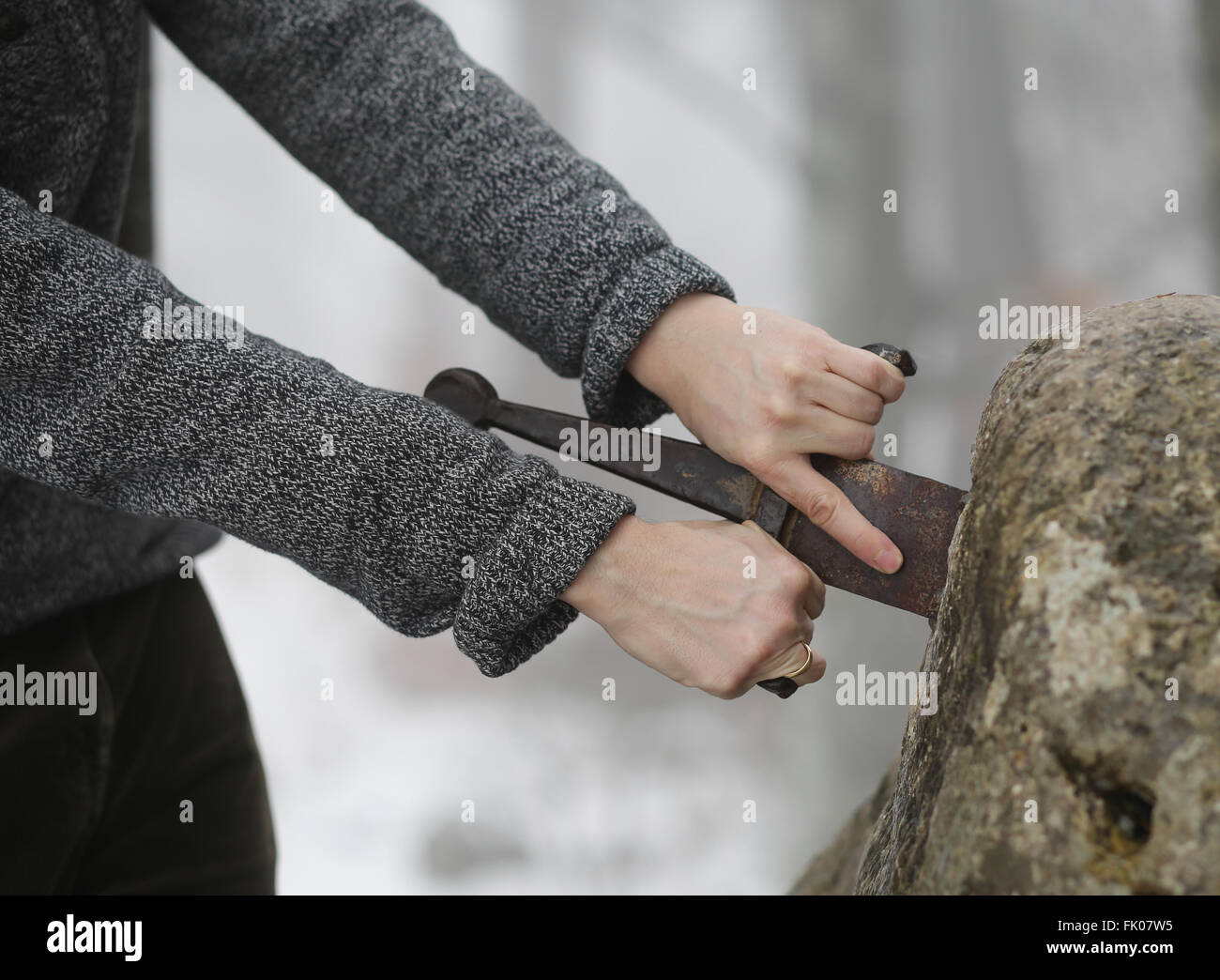 Hand des tapferen Ritters versucht, das magische Schwert Excalibur in den Stein zu entfernen Stockfoto