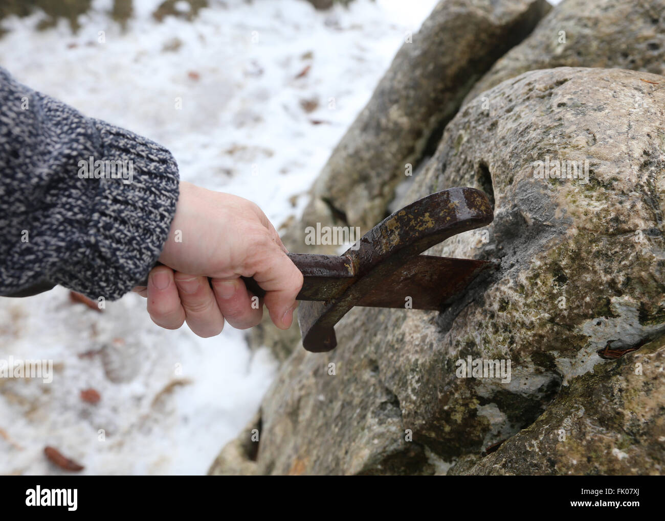 Hand des tapferen Ritters versucht, das magische Schwert Excalibur in den Stein zu entfernen Stockfoto