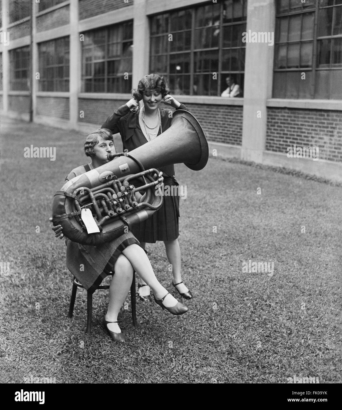 Frau spielt Tuba während einer anderen Frau ist ihre Ohren, USA, ca. 1928 einstecken. Stockfoto