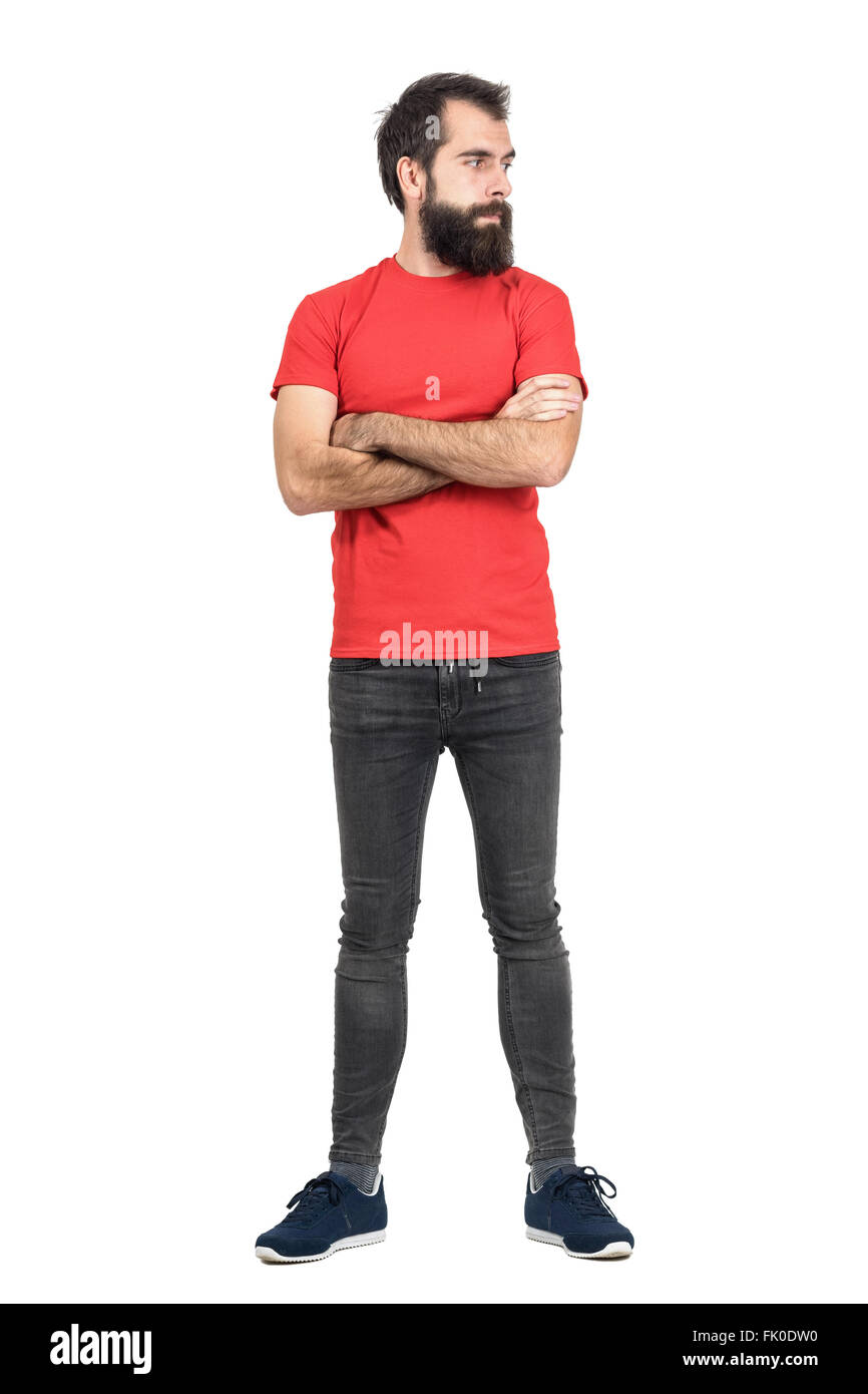 Junge bärtige Mann im roten T-shirt mit verschränkten Armen wegsehen. Ganzkörper-Länge-Porträt über weiße Studio-Hintergrund isoliert Stockfoto