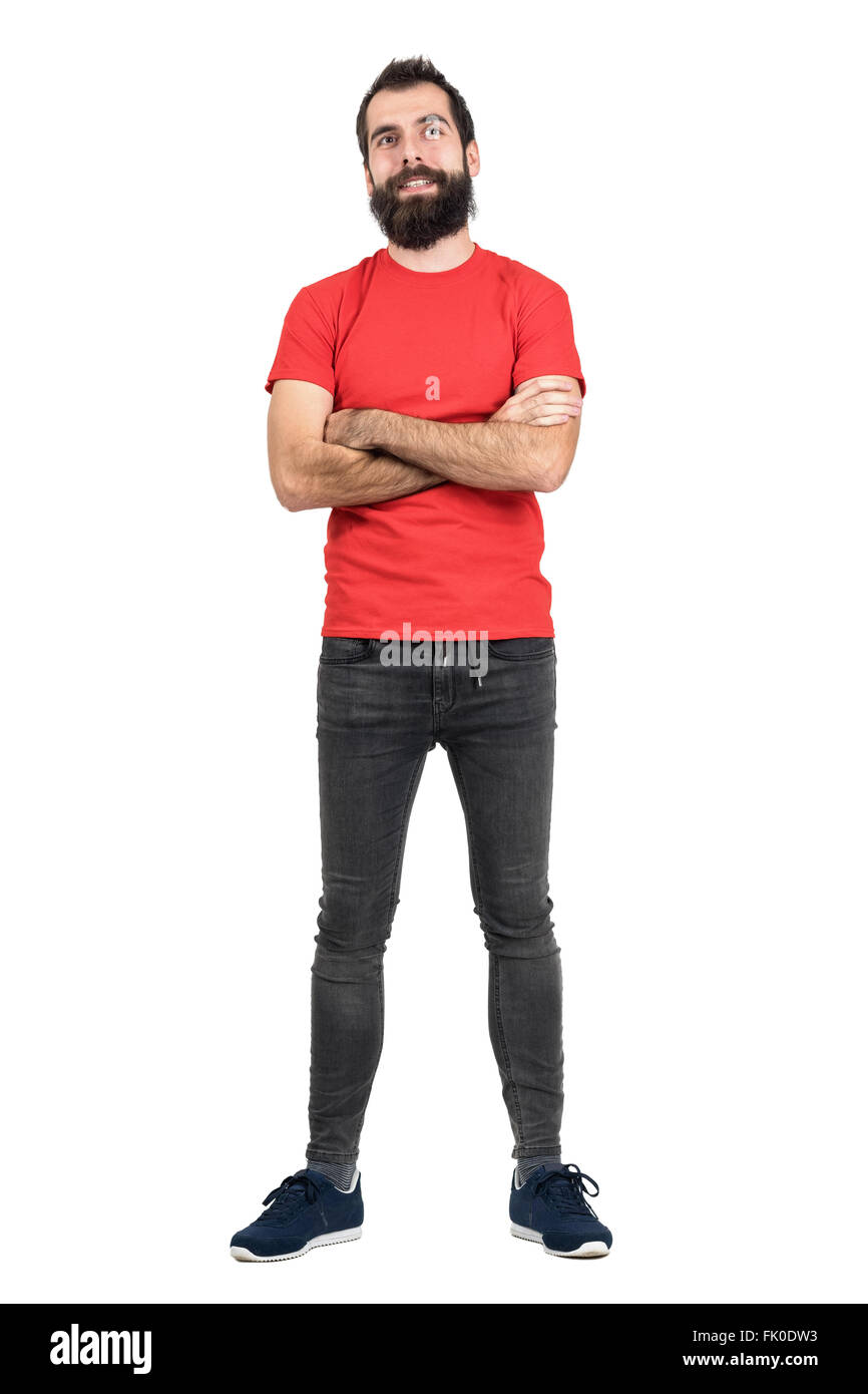 Hipster in rotes T-shirt mit verschränkten Armen lächelnd nachschlagen. Ganzkörper-Länge-Porträt über weiße Studio-Hintergrund isoliert. Stockfoto