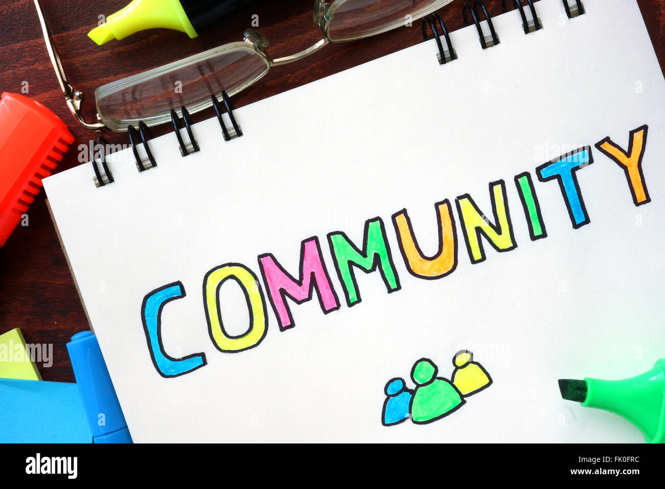 Community-Konzept in ein Notizbuch auf einem Holztisch geschrieben. Stockfoto