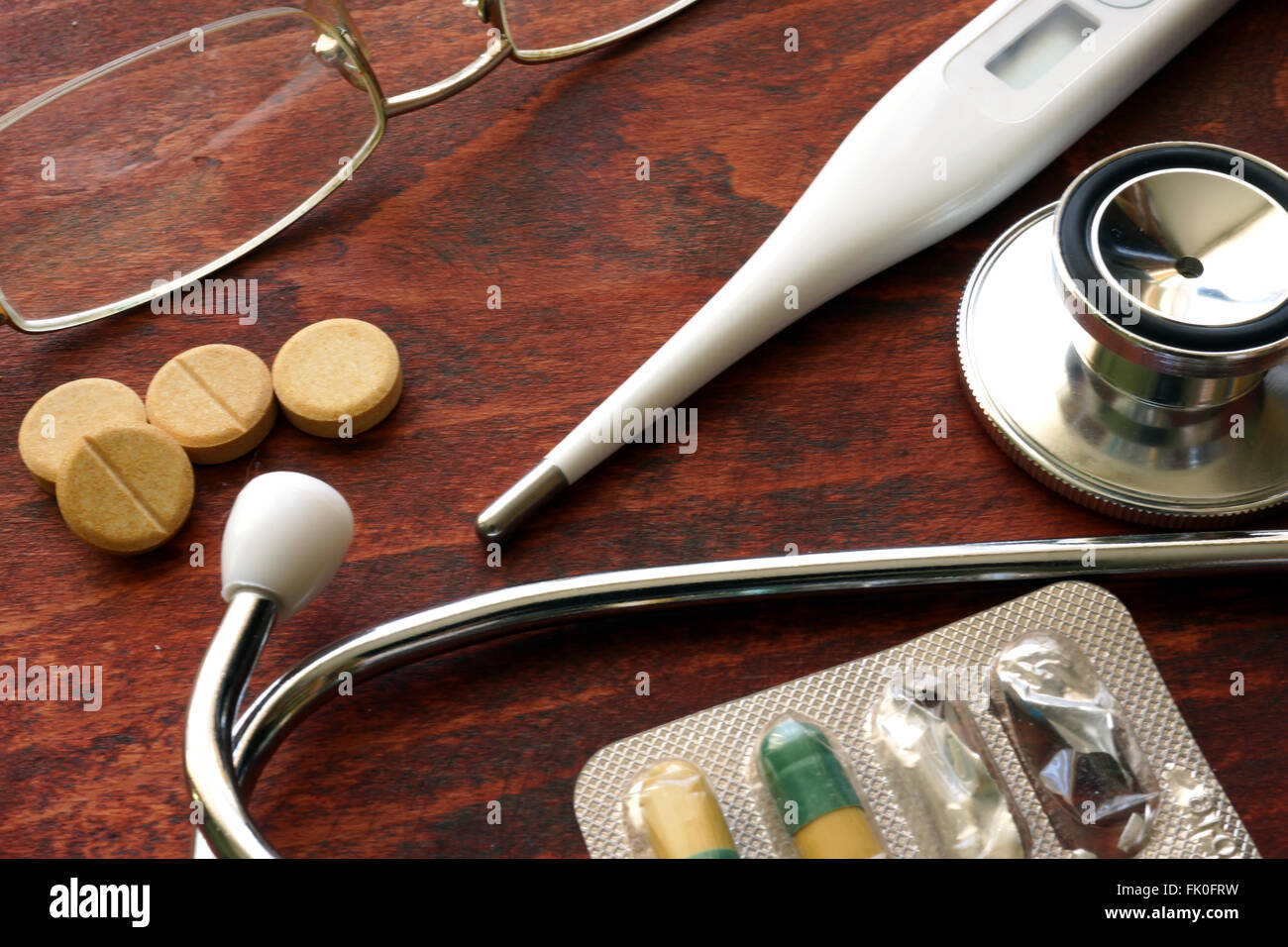 Stethoskop und Thermometer mit Pillen auf dem Schreibtisch. Medizinischer Hintergrund. Stockfoto