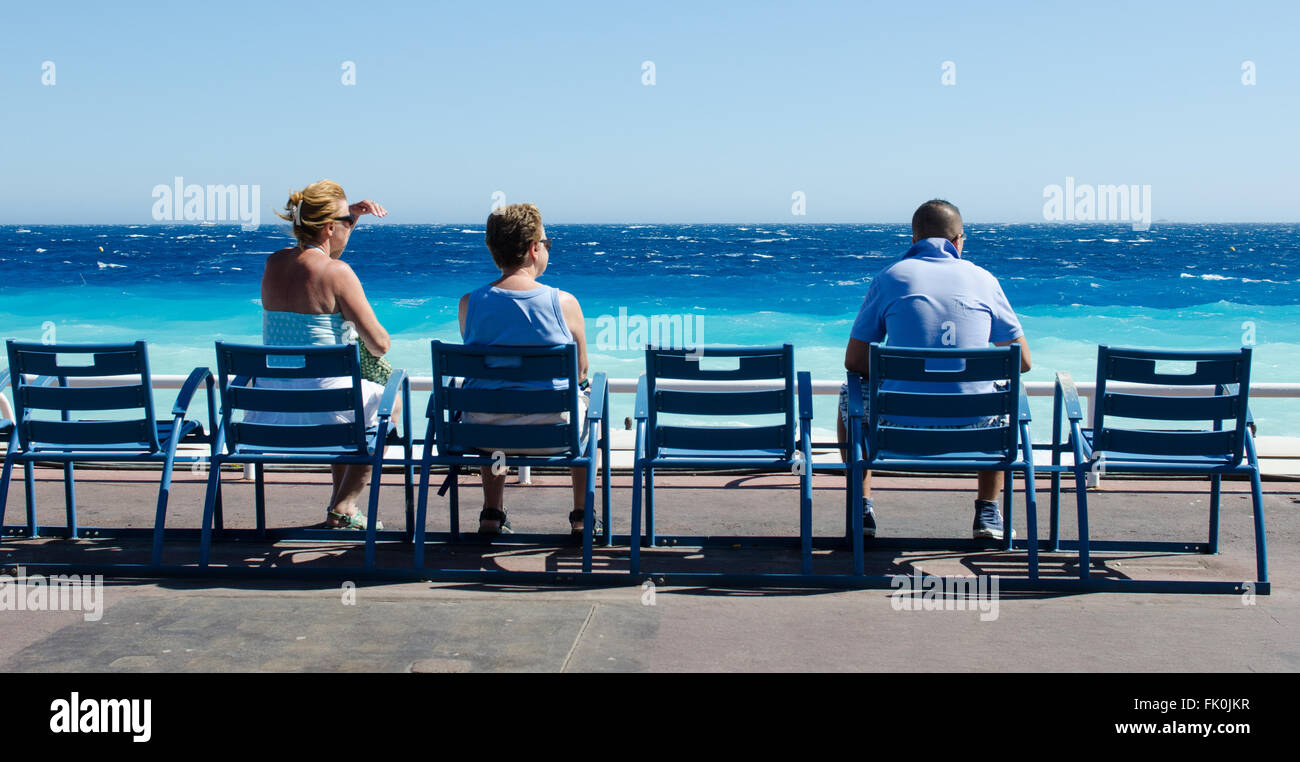 Touristen, die auf einer Bank, auf der Promenade des Anglais in Nizza am Mittelmeer suchen Stockfoto