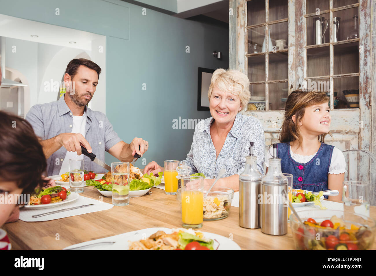 Lächelnde Oma beim Sitzen am Esstisch Stockfoto