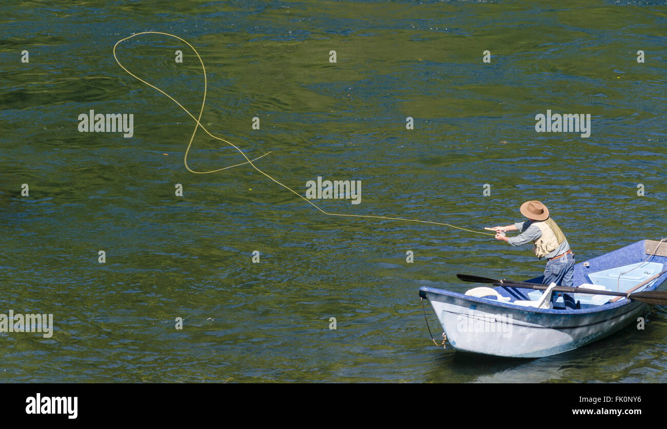 Ein einsamer Fischer in einem Drift-Boot von oben gesehen wirft seine Linie über dem Wasser. Stockfoto
