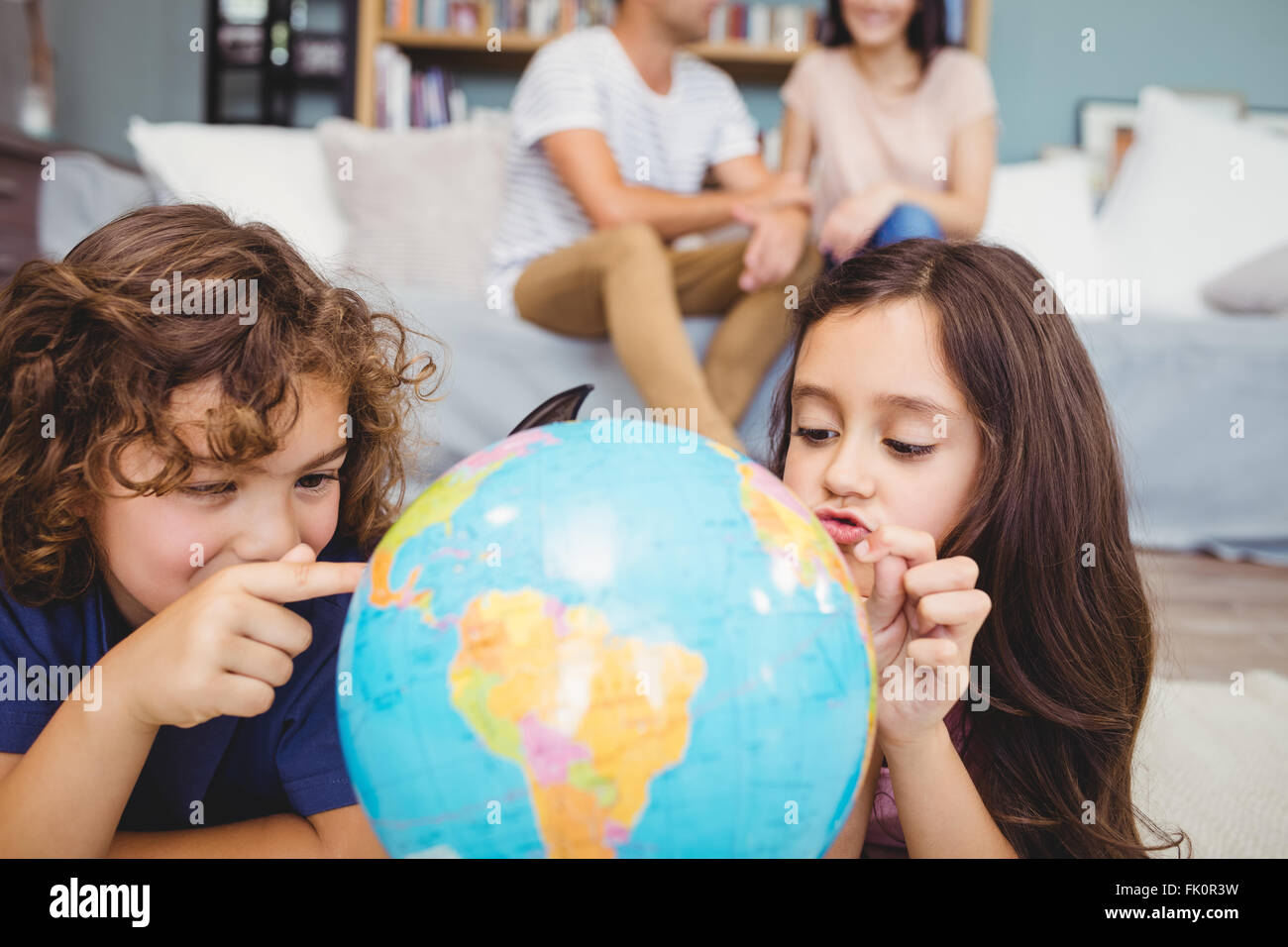 Kinder zeigen im Globe während die Eltern im Hintergrund Stockfoto