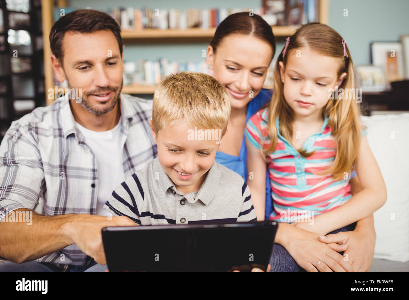 Familie lächelnd bei der Verwendung von Technologien zu Hause auf sofa Stockfoto