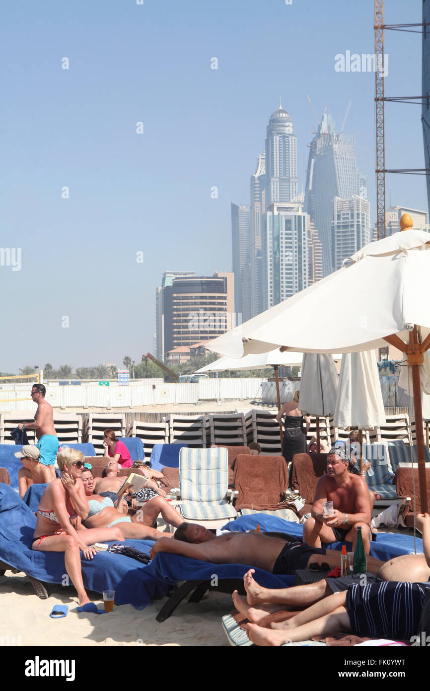 Westliche Touristen genießen die Februarsonne in Dubai, klatschen aus, baden in der Sonne, ruhen sich am Strand aus und trinken Bier Stockfoto