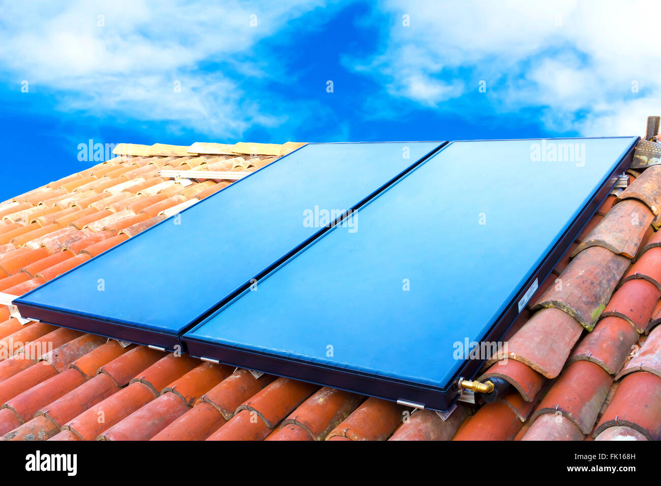 Sonnenkollektoren auf dem Dach eines Hauses mit blauem Himmelshintergrund installiert Stockfoto