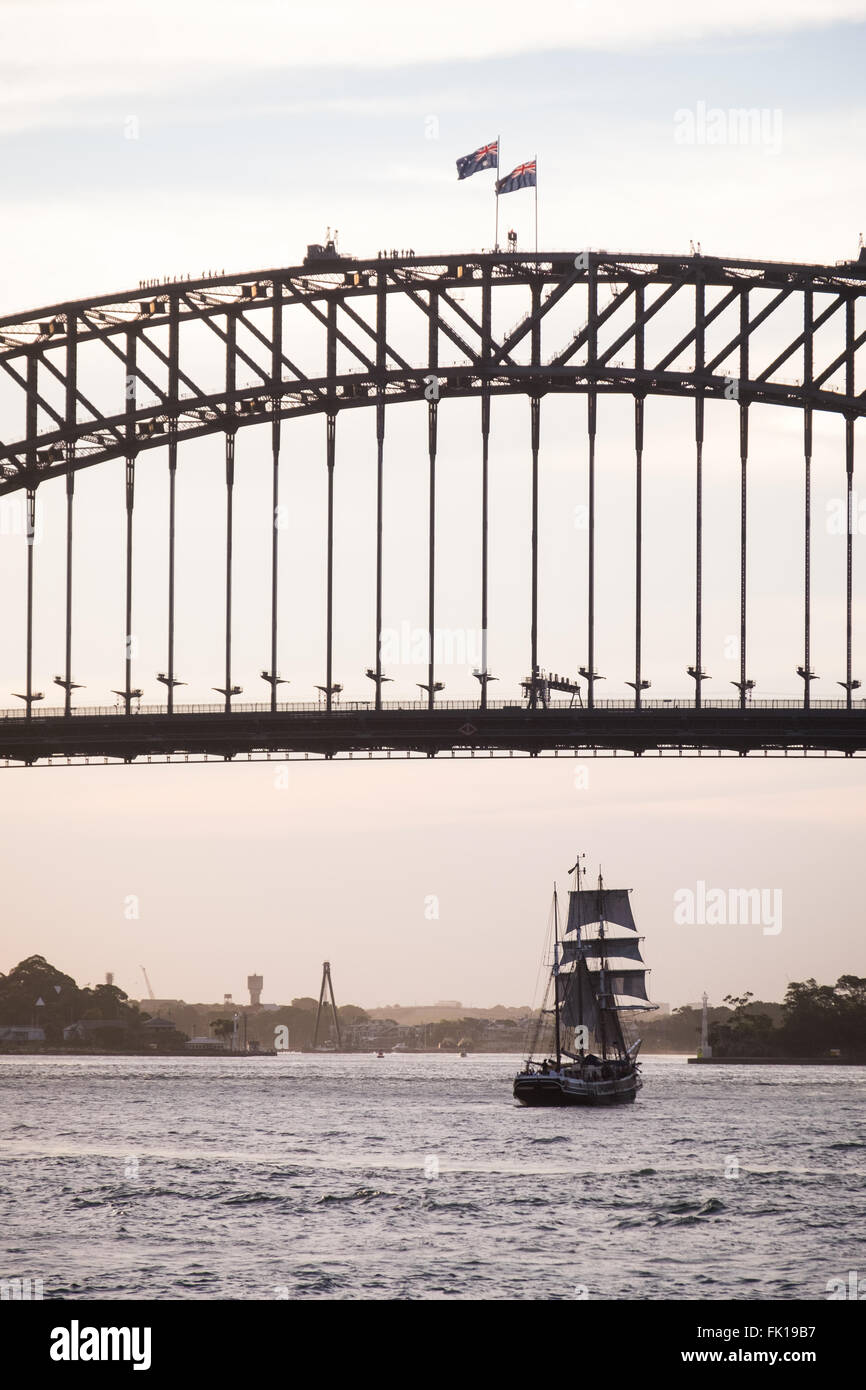 Ein altes Segelschiff unterquert die Sydney Harbour Bridge Stockfoto