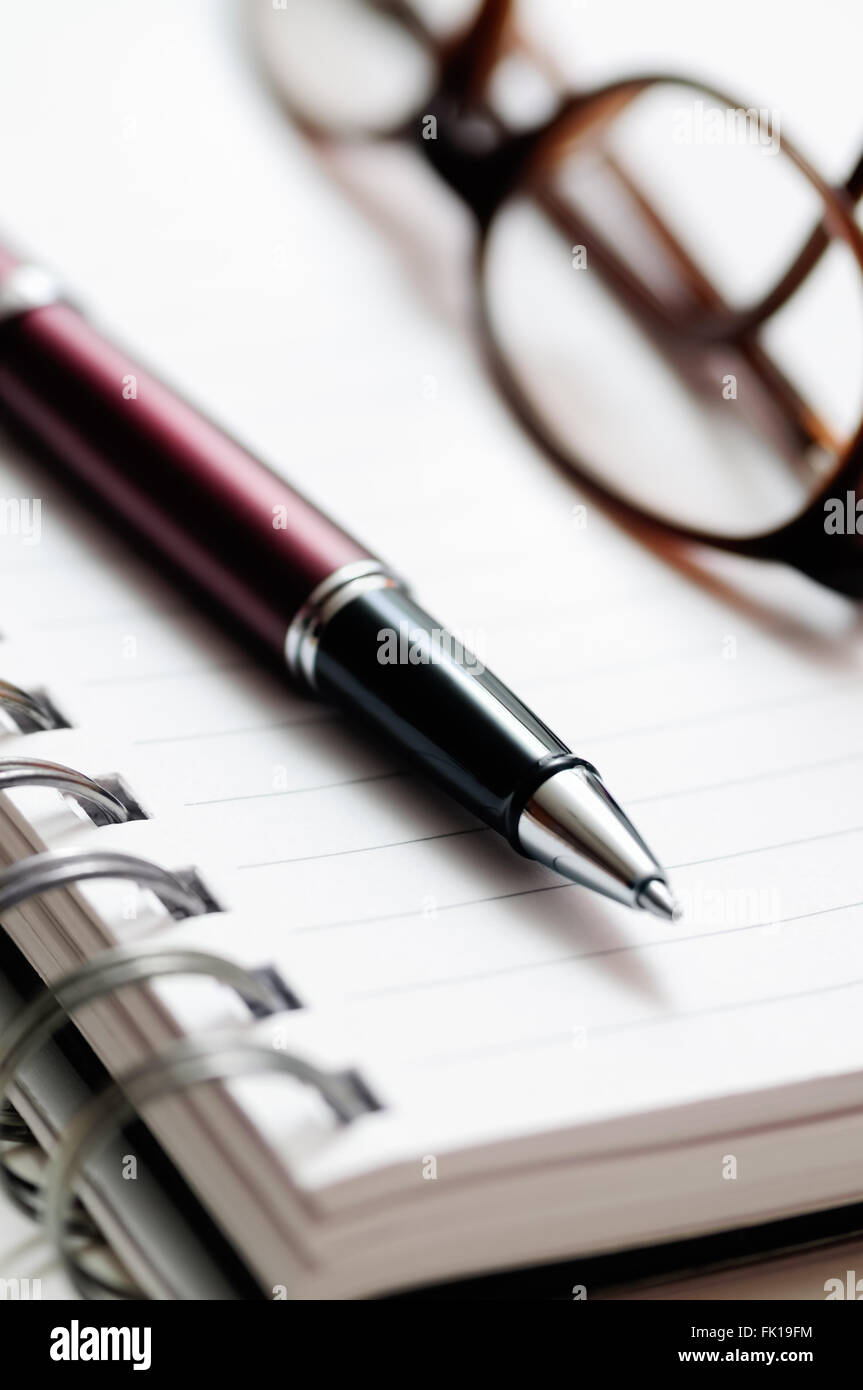 Kugelschreiber und verschreibungspflichtigen Brillen auf Papier ausgekleidet Spirale notebook Stockfoto