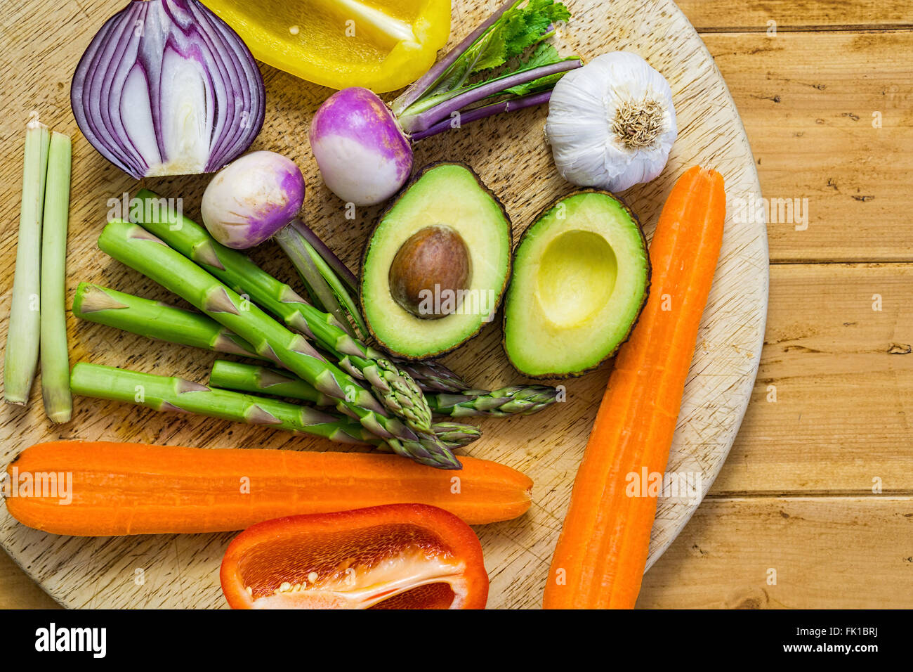 Frisches Gemüse in Scheiben geschnitten auf einem Holztisch, Rundweg, Spargel, Avocado, Paprika, Zwiebel Stockfoto