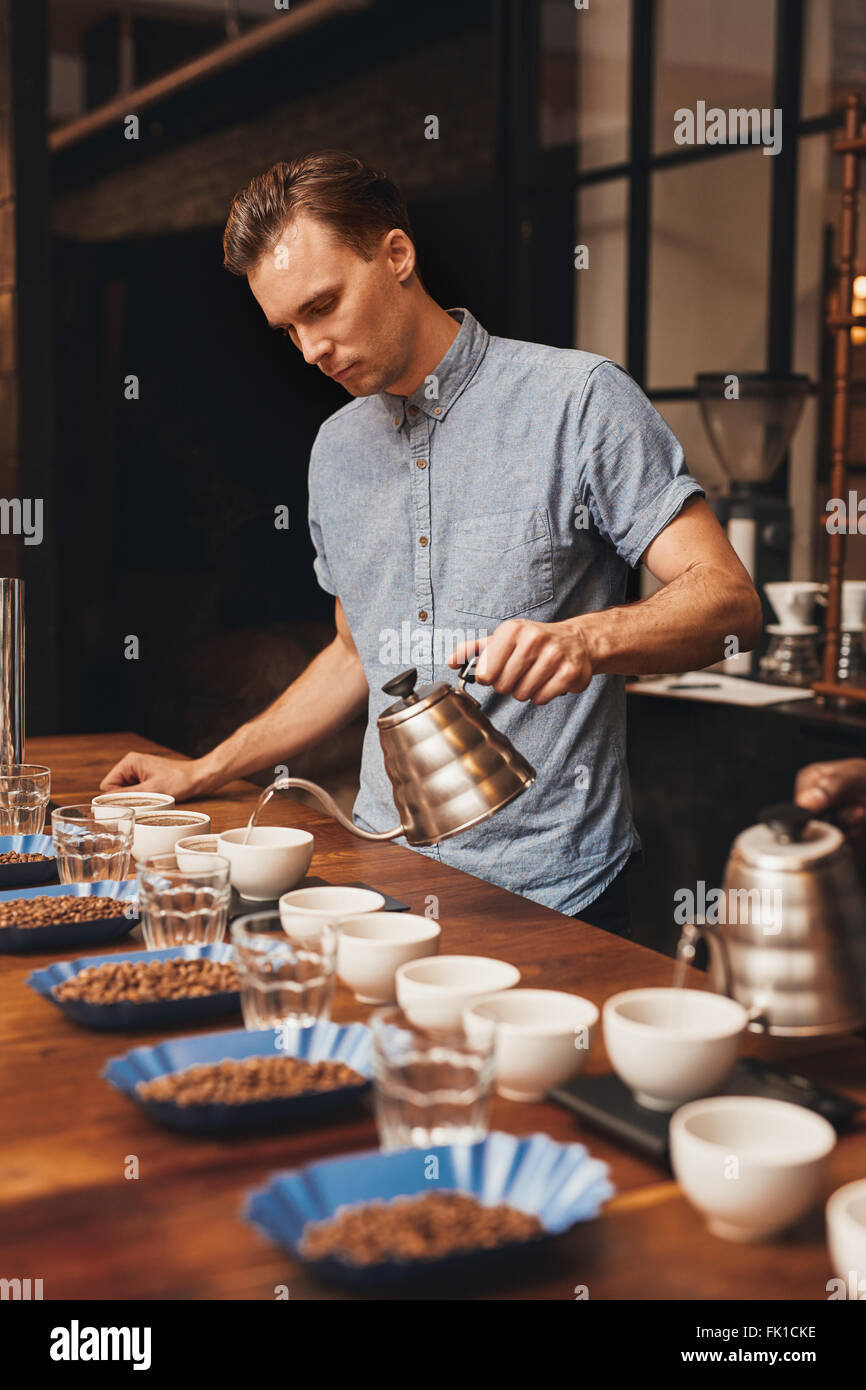 Vorbereitung auf eine Verkostung mit Reihen von Tassen Kaffee Barista Stockfoto
