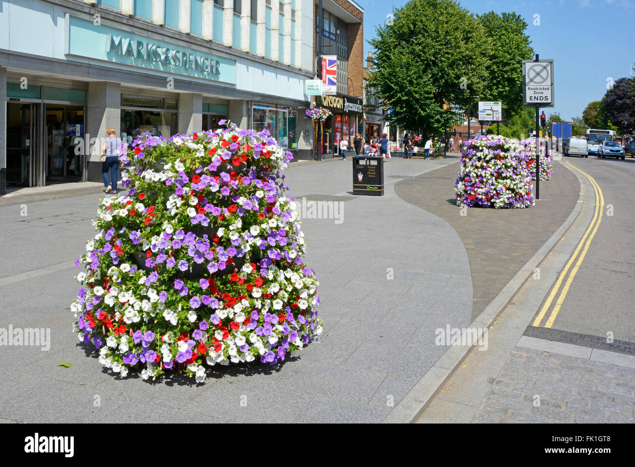 Brentwood Stadtzentrum shopping High Street breiten Bürgersteig mit Sommerblume vor Marks & Spencer Shop Blumen durch Gemeinderat anzeigen Stockfoto