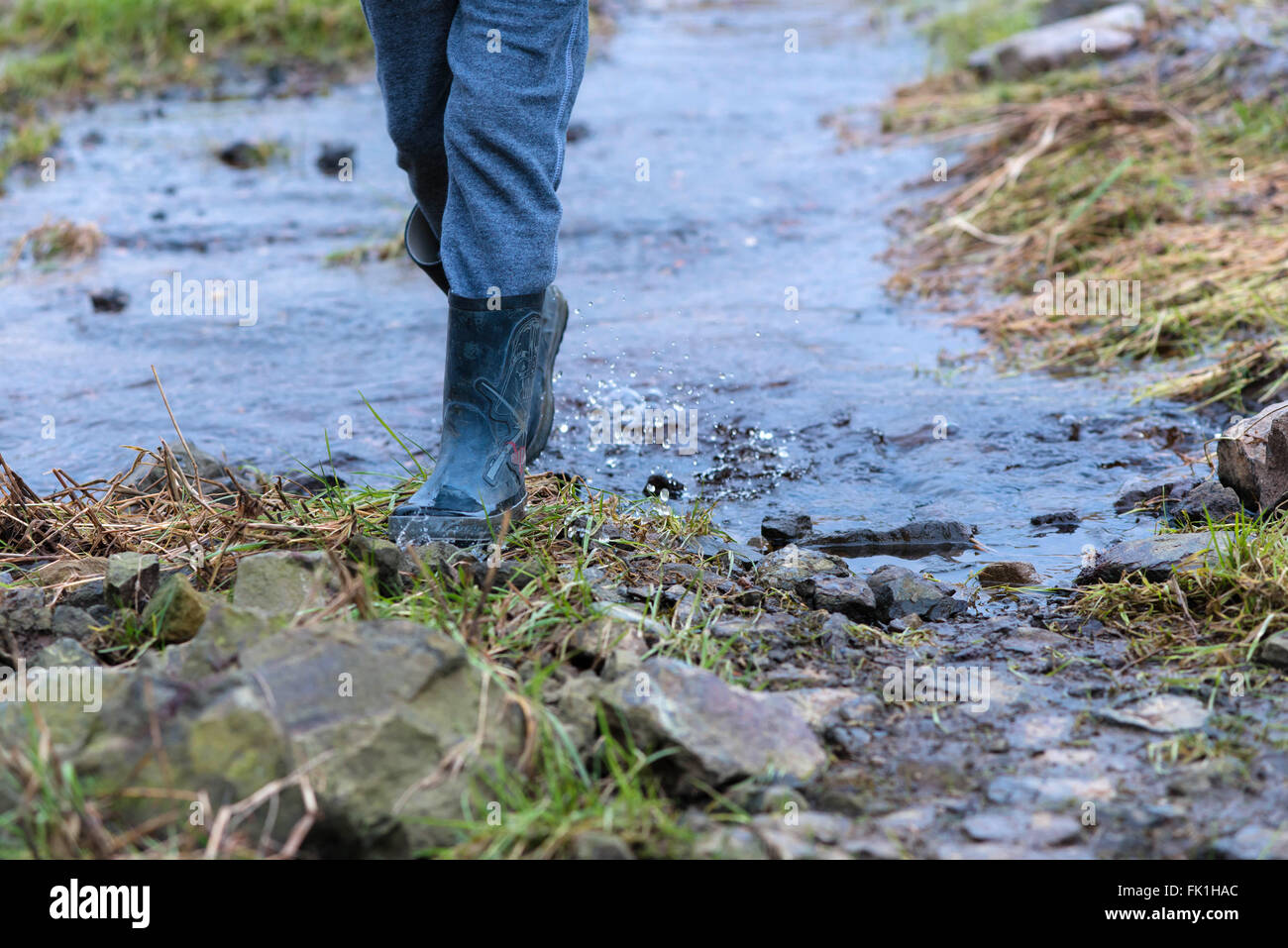 Kind zu Fuß durch Stream mit Gummistiefeln auf Stockfoto
