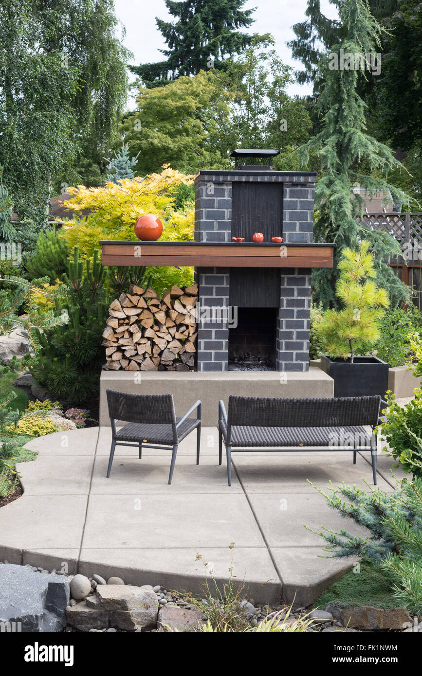 Großer, individuell gestaltete Kamin mit grauen Ziegeln und viel Brennholz setzt sich auf eine einladende Terrasse in einem pazifischen Nordwesten zurück Stockfoto