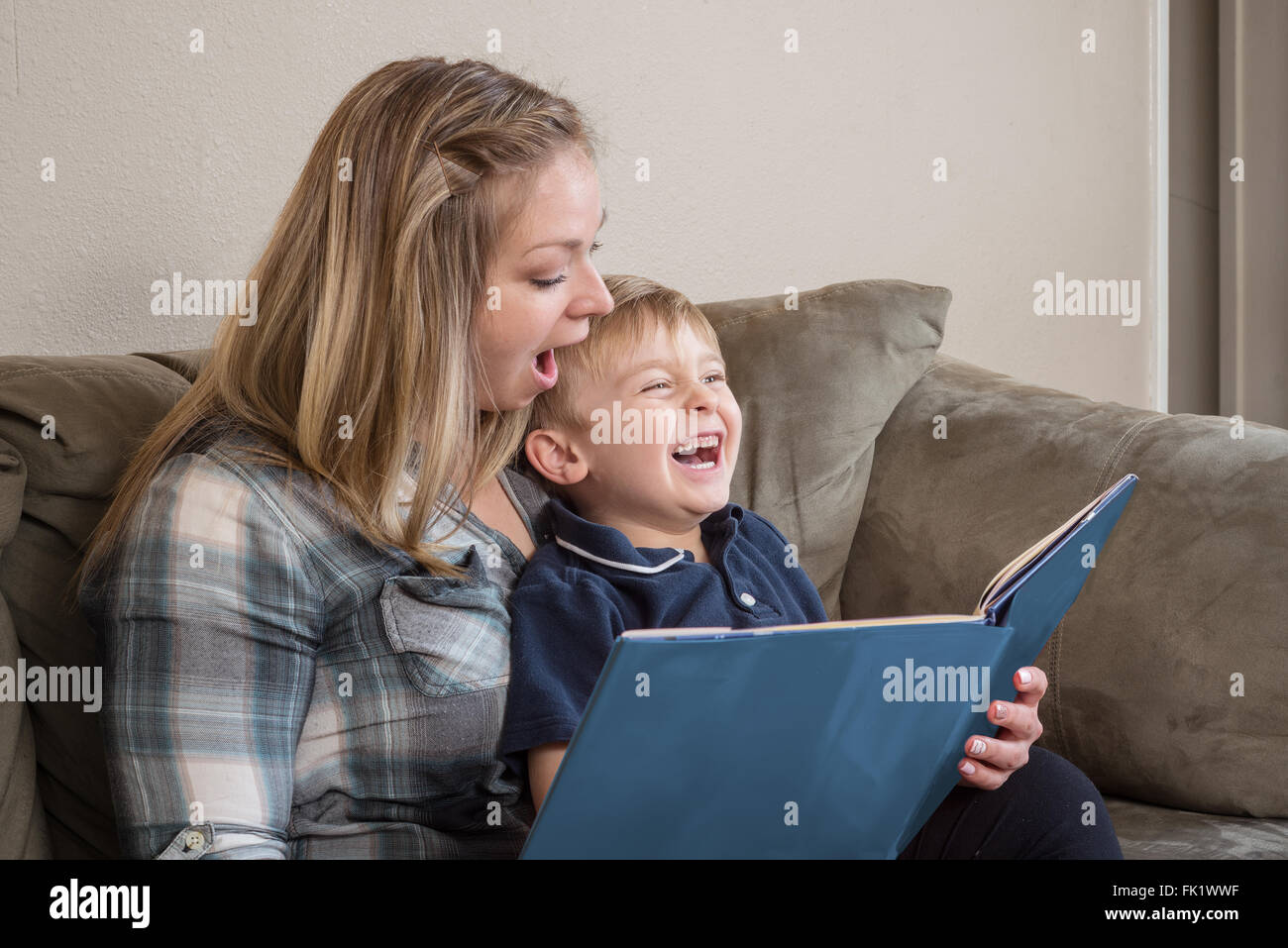 Ein kleiner Junge lacht, als seine Mutter ihm eine Geschichte mit großen Ausdruck liest. Stockfoto