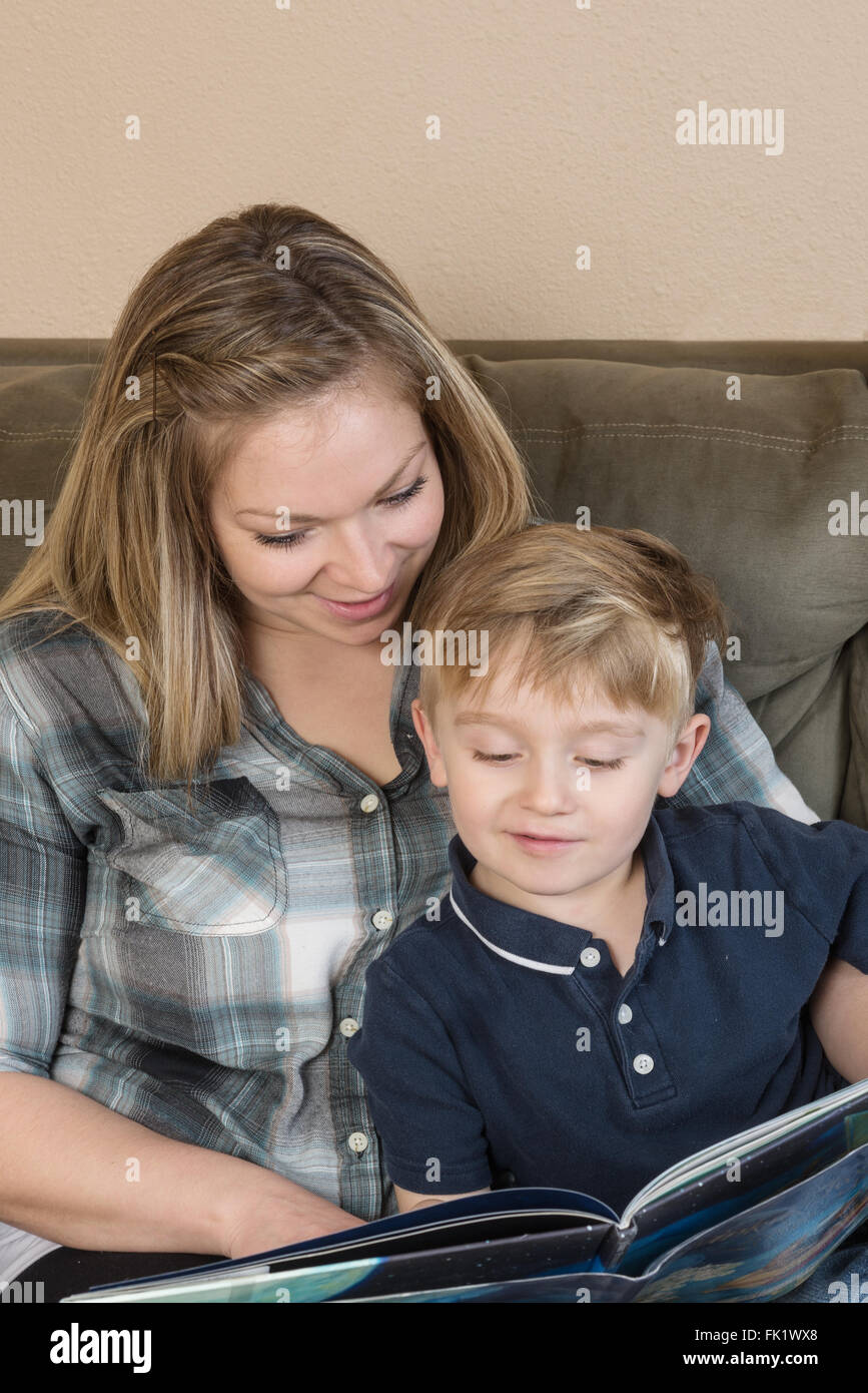 Eine Mutter und ihr junger Sohn kuscheln zusammen, als sie ihm eine Geschichte vorliest. Stockfoto