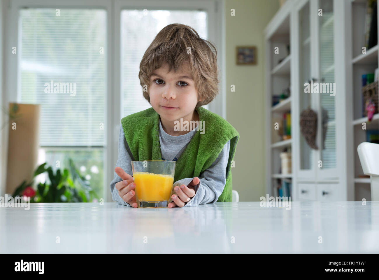 Niedlichen kleinen Jungen am Tisch trinken Orangensaft zum Frühstück. Gesunde Lebensweise, Ernährung und eine gesunde Ernährung Stockfoto