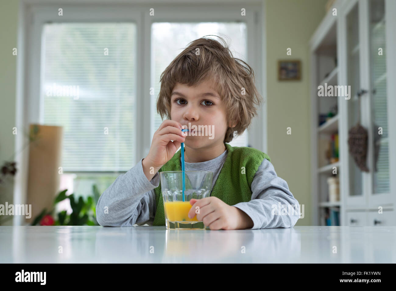 Niedlichen kleinen Jungen am Tisch trinken Orangensaft zum Frühstück. Gesunde Lebensweise, Ernährung und eine gesunde Ernährung Stockfoto