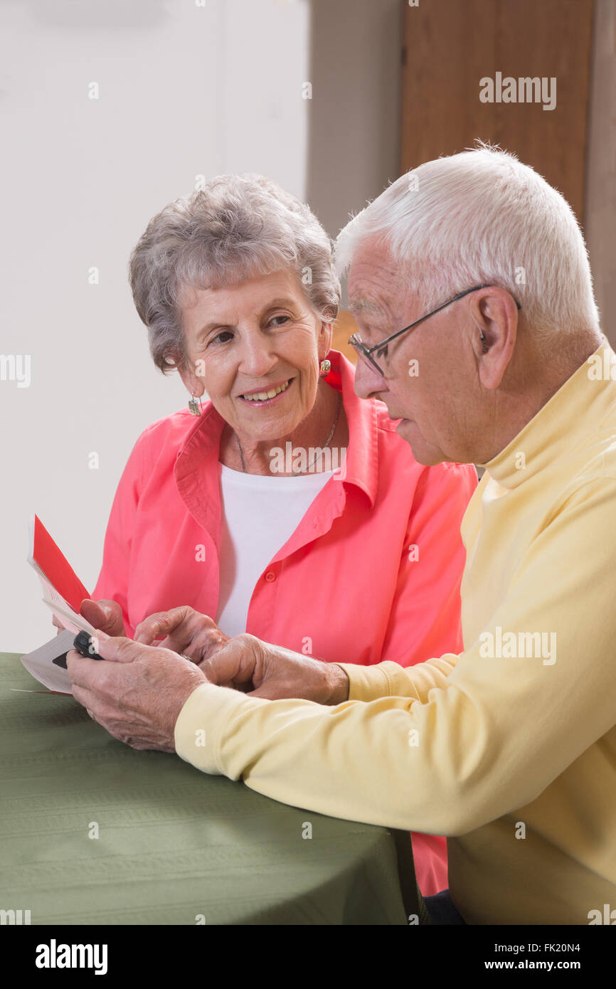 Eine Frau schaut ihr Mann von 64 Jahren liebevoll, wie sie lernen, ihr neue Handy zu verwenden. Stockfoto