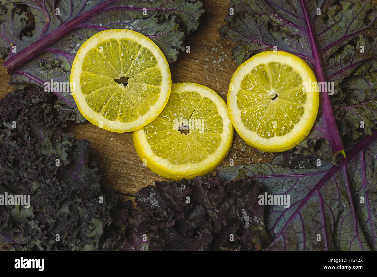 In Scheiben geschnittene Zitrone und Kale Salat auf Holz Hintergrund Stockfoto