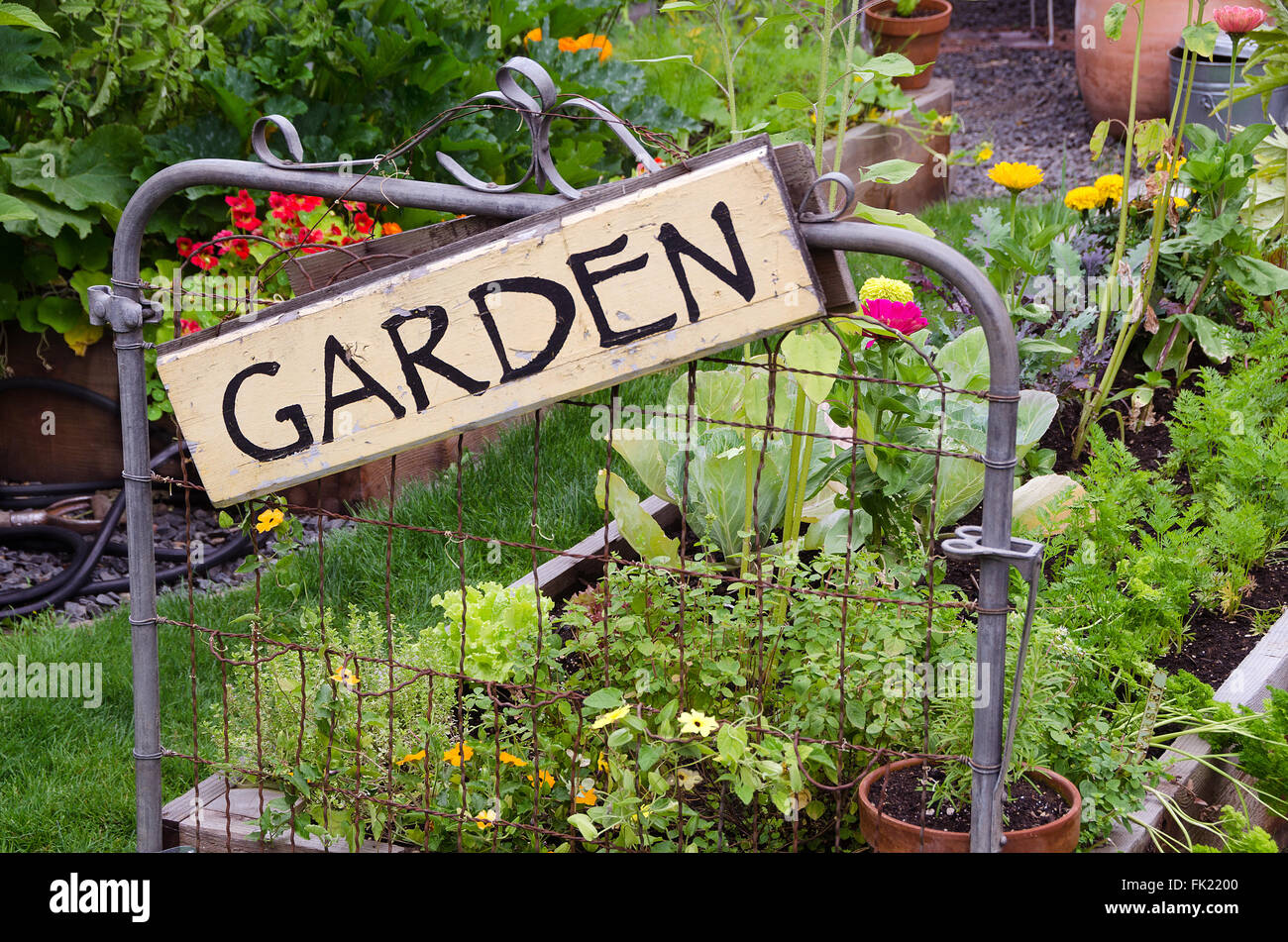 Zwei Garten Hochbeete gefüllt mit Blumen und Gemüse sind in kleinen Hinterhof gelegen. Eine schöne rustikale Schild hängen jaunti Stockfoto