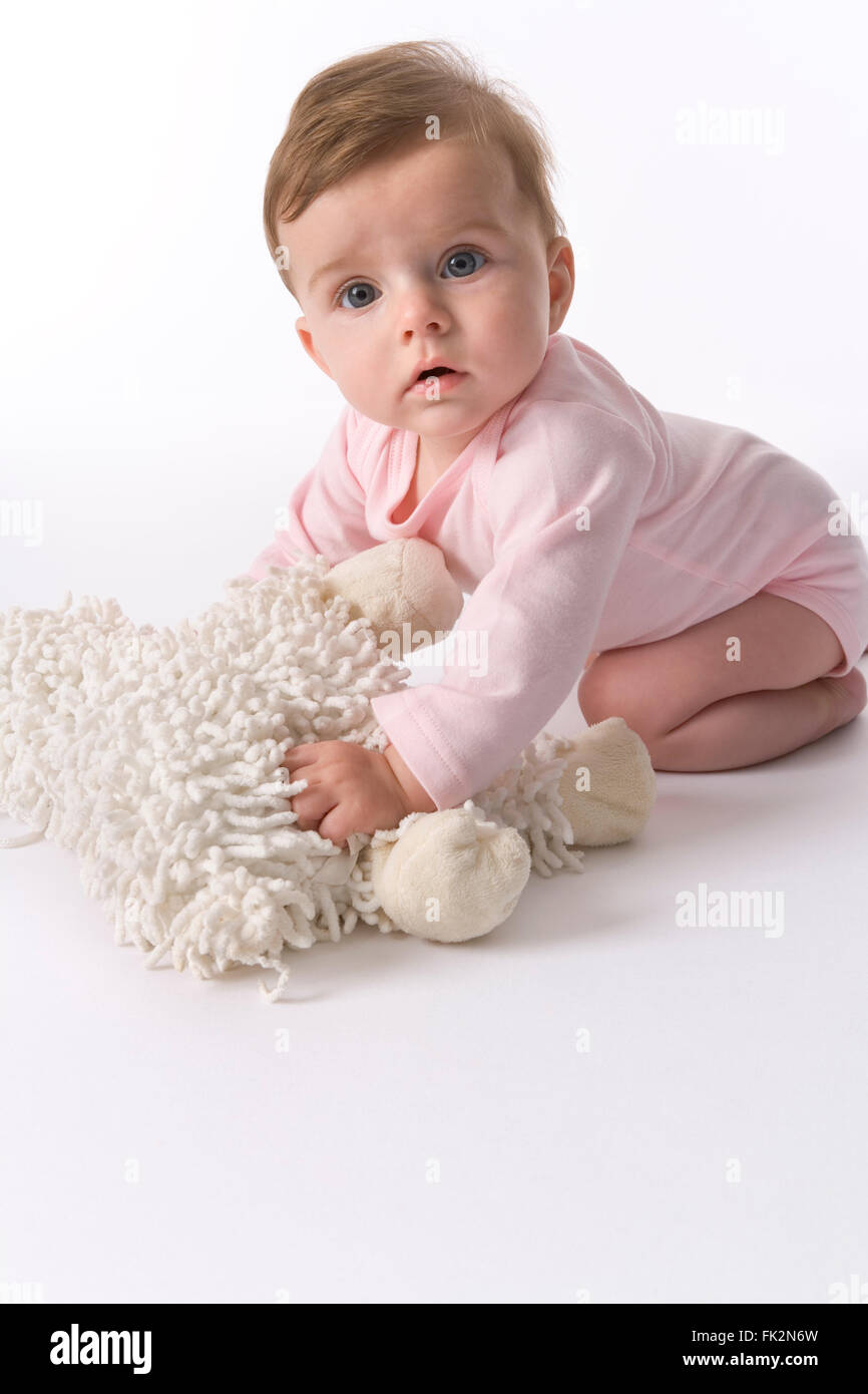 Baby Mädchen sitzen auf der Etage mit Her Toy Schafe auf weißem Hintergrund Stockfoto