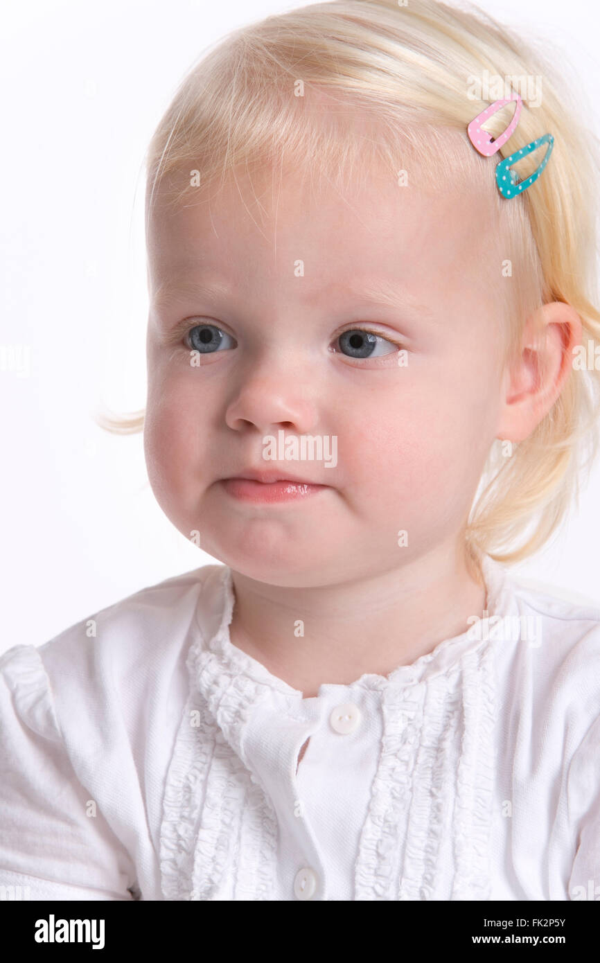 Portrait Of A blonde Kleinkind Mädchen mit A zaghaft Expression auf weißem Hintergrund Stockfoto