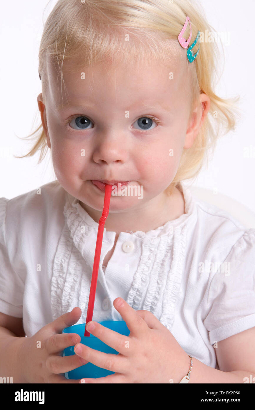 Kleinkind Mädchen ist trinken Limonade mit A Stroh auf weißem Hintergrund Stockfoto