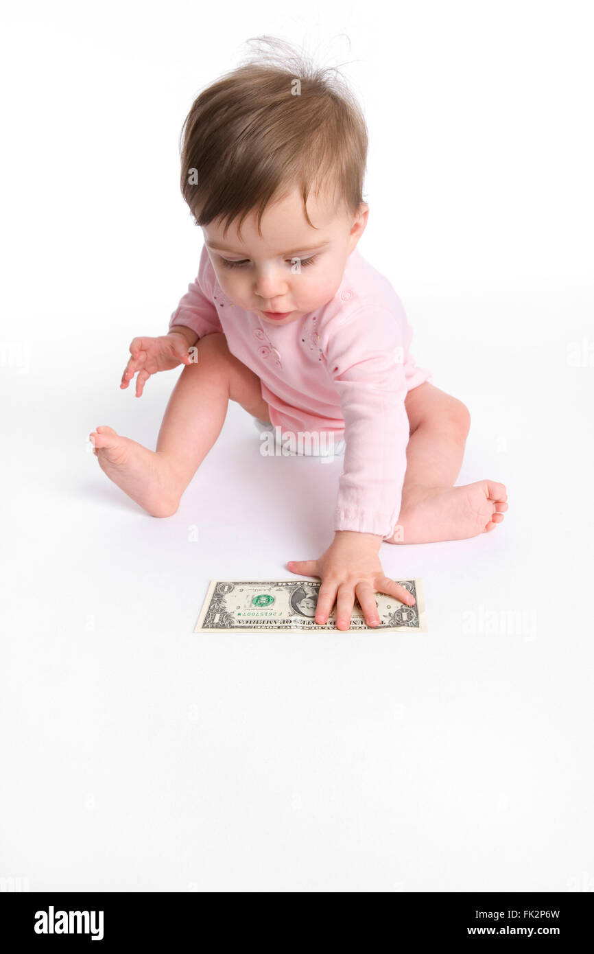 Babymädchen ist Abholung einen Dollar vom Boden auf weißem Hintergrund Stockfoto