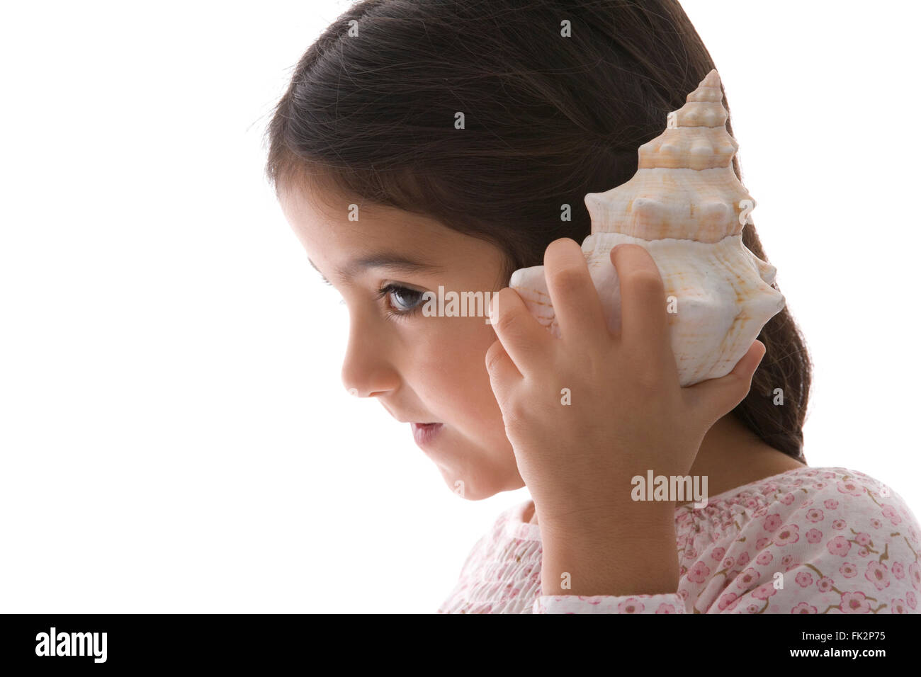 Kleine Mädchen ist zuhören, A große Muschel auf weißem Hintergrund Stockfoto