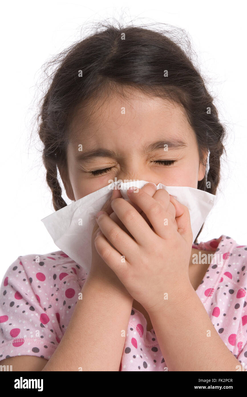 Kleines Mädchen bläst ihre Nase in ein Papiertaschentuch auf weißem Hintergrund Stockfoto
