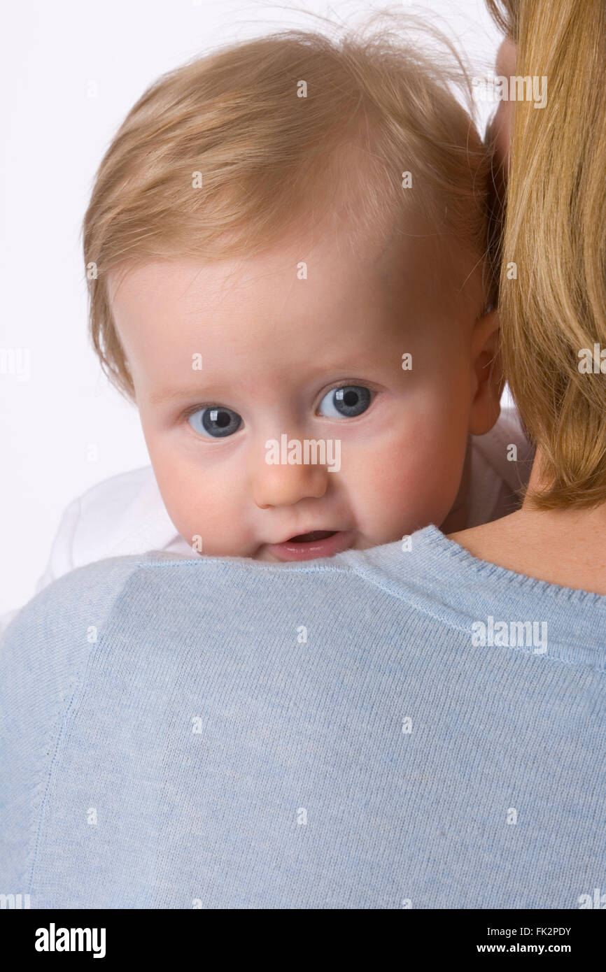 Baby Girl ist auf der Suche über Mütter Schulter auf weißem Hintergrund Stockfoto