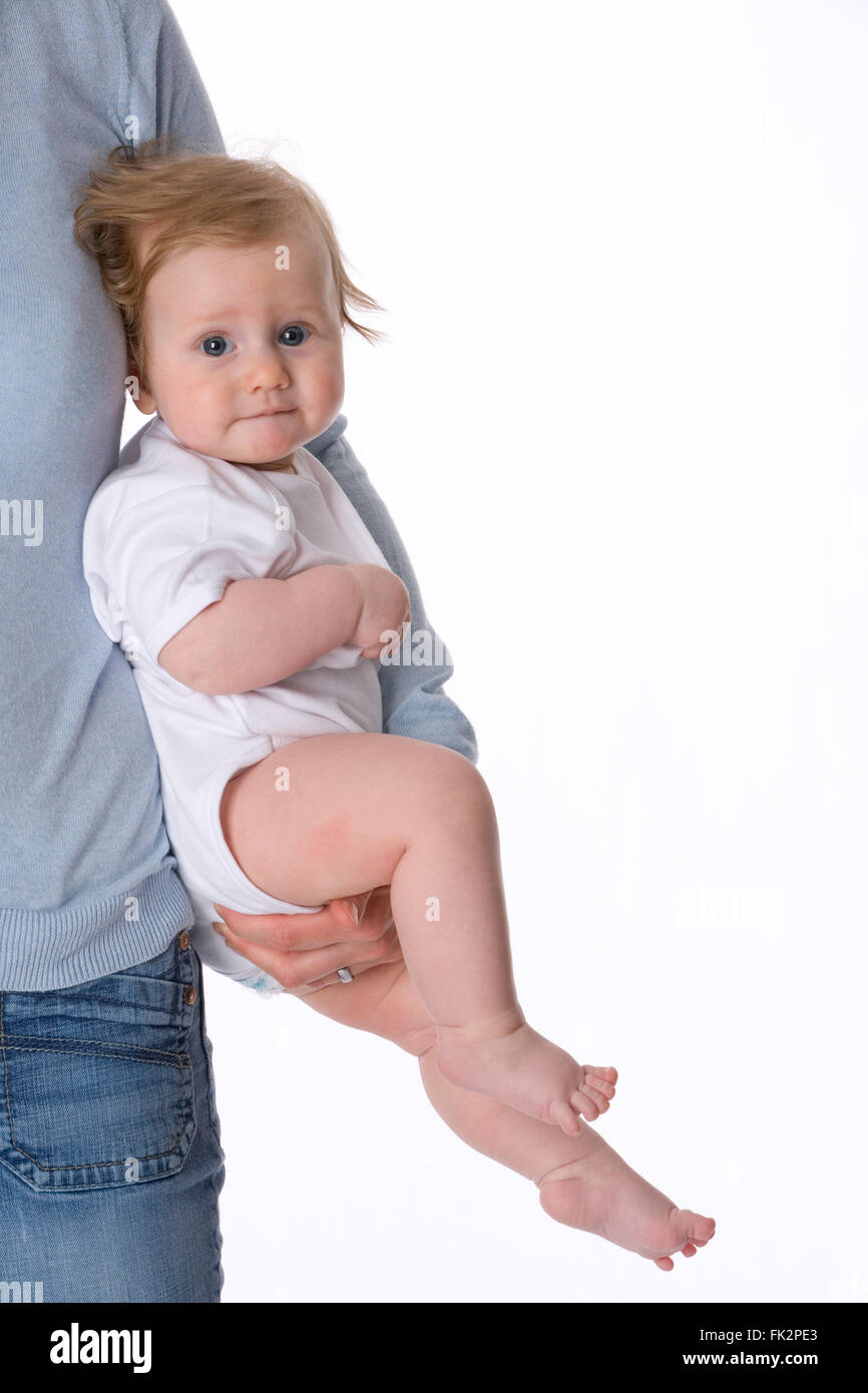 Babymädchen wird von ihrer Mutter auf weißem Hintergrund durchgeführt. Stockfoto