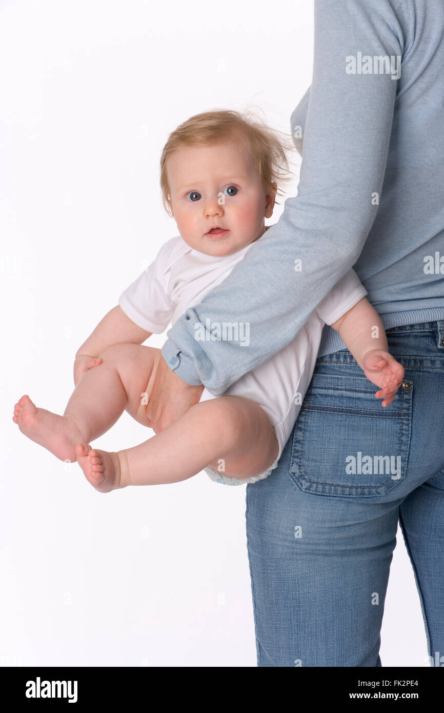 Babymädchen wird von ihrer Mutter auf weißem Hintergrund durchgeführt. Stockfoto