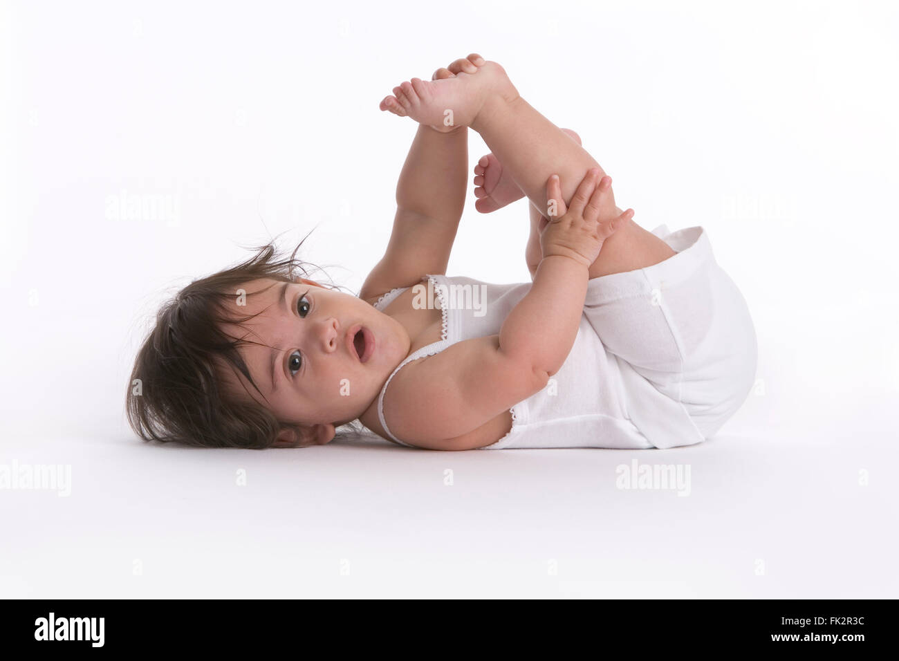Baby Mädchen liegen auf The Stock mit mit einem Bein, wie Fitness auf weißem Hintergrund Stockfoto