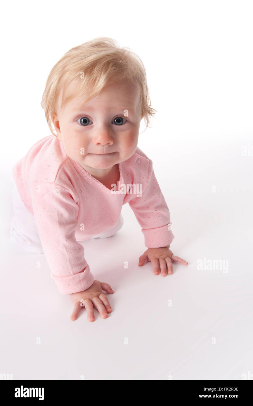 Baby Girl ist auf dem Boden kriechen und schaut in die Kamera auf weißem Hintergrund Stockfoto