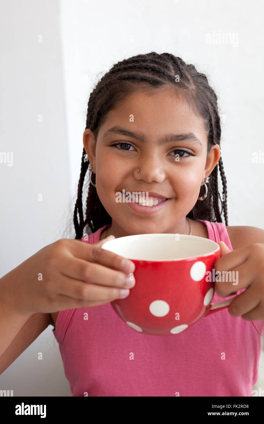 Kleines Mädchen mit einer großen Tasse Tee und einem glücklichen Lächeln auf weißem Hintergrund Stockfoto