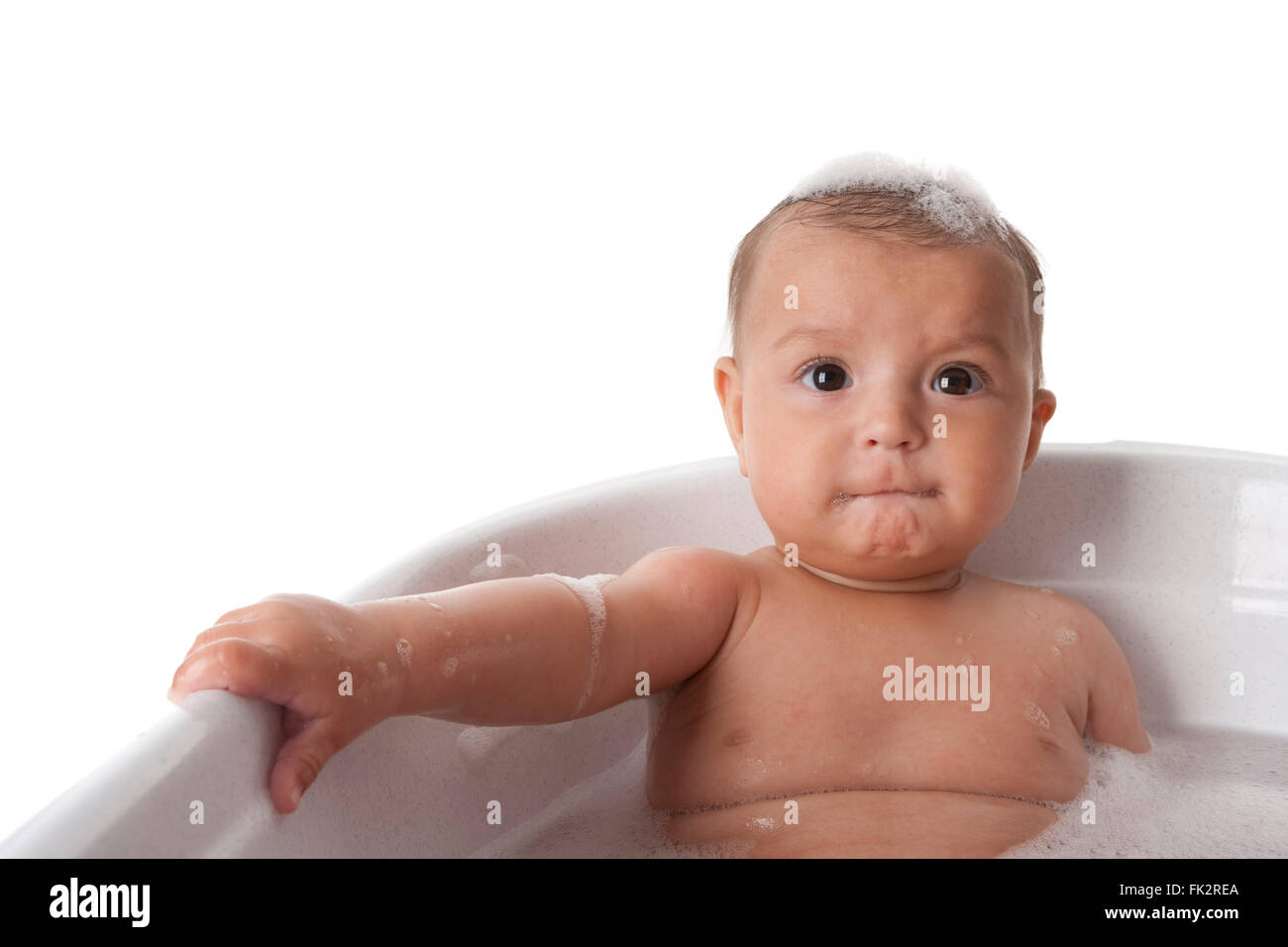 Babymädchen sitzen in der Badewanne mit Schaum auf weißem Hintergrund Stockfoto