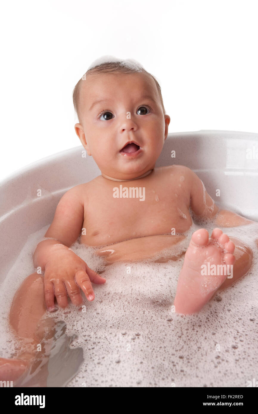 Babymädchen sitzen in der Badewanne mit Schaum auf weißem Hintergrund Stockfoto