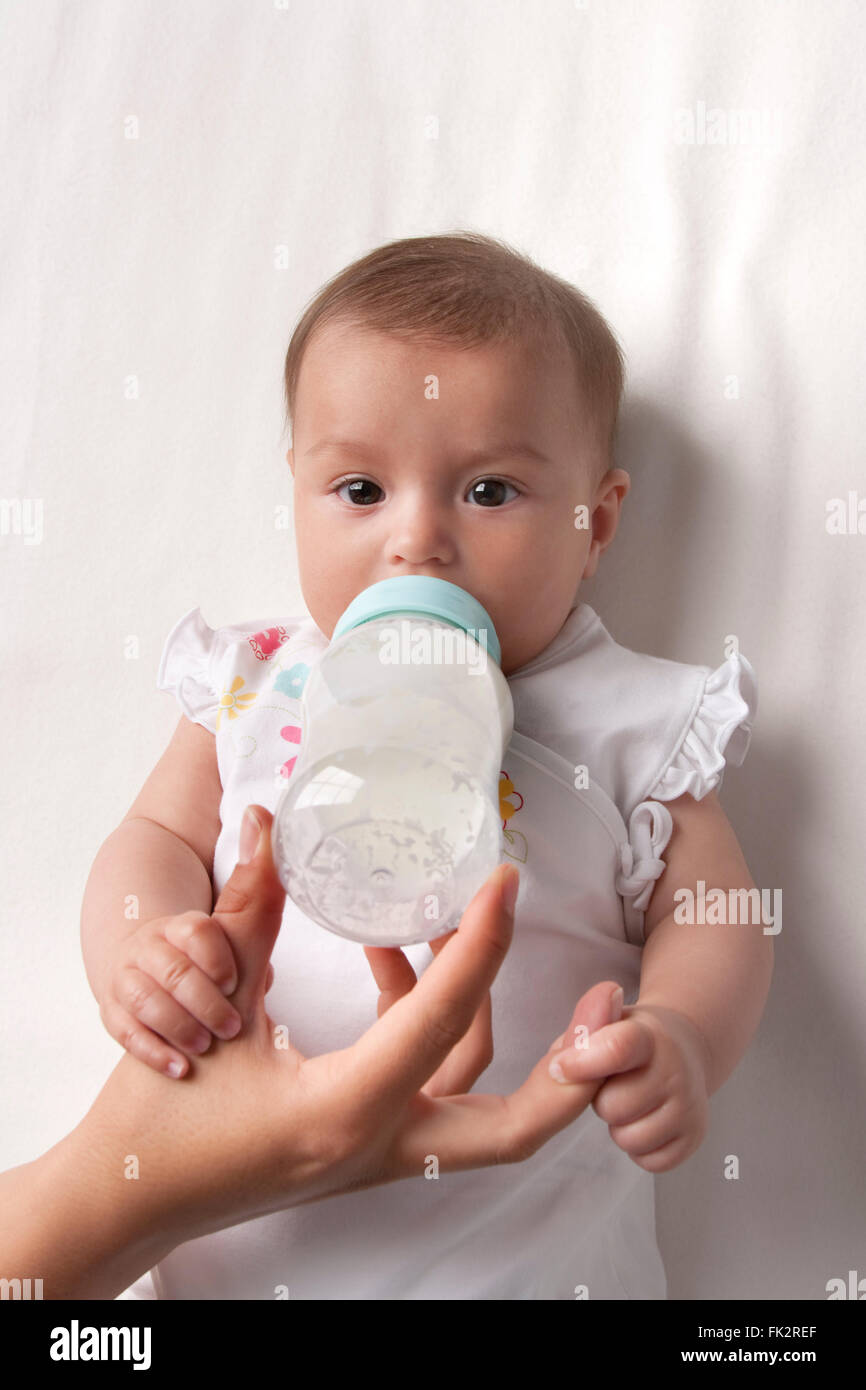 Babygirl Getränke aus einem Baby-Flasche Betrieb Eltern hand Stockfoto