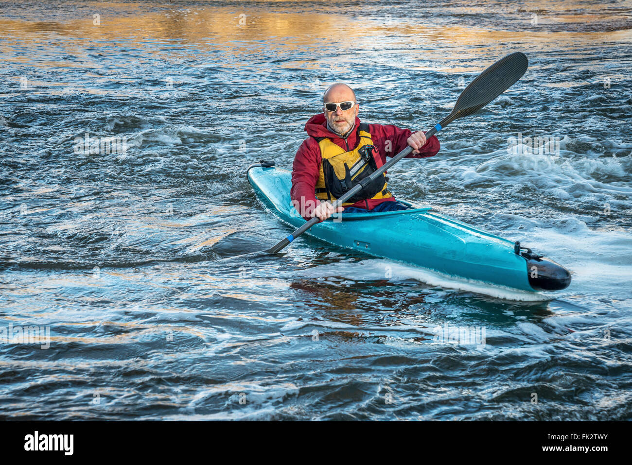 Senioren männlich eine Wildwasser-Kajak auf einem turbulenten Fluss paddeln Stockfoto